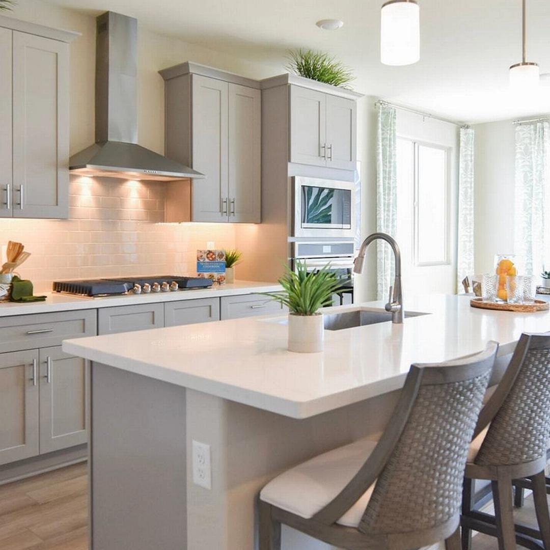 Contemporary kitchen with gray shaker cabinets, white quartz island, bar stools, and stainless appliances at North Ridge Pronghorn Ranch in Prescott Valley AZ