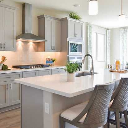 Contemporary kitchen with gray shaker cabinets, white quartz island, bar stools, and stainless appliances at North Ridge Pronghorn Ranch in Prescott Valley AZ