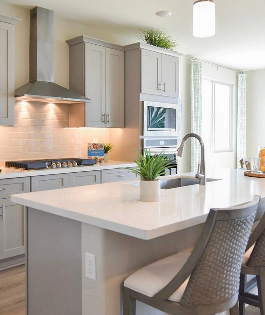 Contemporary kitchen with gray shaker cabinets, white quartz island, bar stools, and stainless appliances at North Ridge Pronghorn Ranch in Prescott Valley AZ