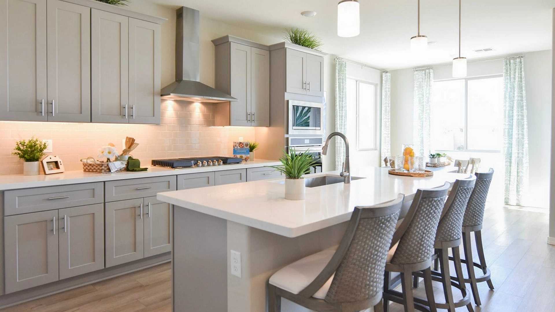 Contemporary kitchen with gray shaker cabinets, white quartz island, bar stools, and stainless appliances at North Ridge Pronghorn Ranch in Prescott Valley AZ