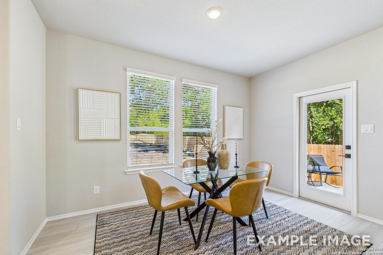 Modern dining room with glass table, yellow upholstered chairs, and backyard view in The Charlotte B home, San Antonio, Texas