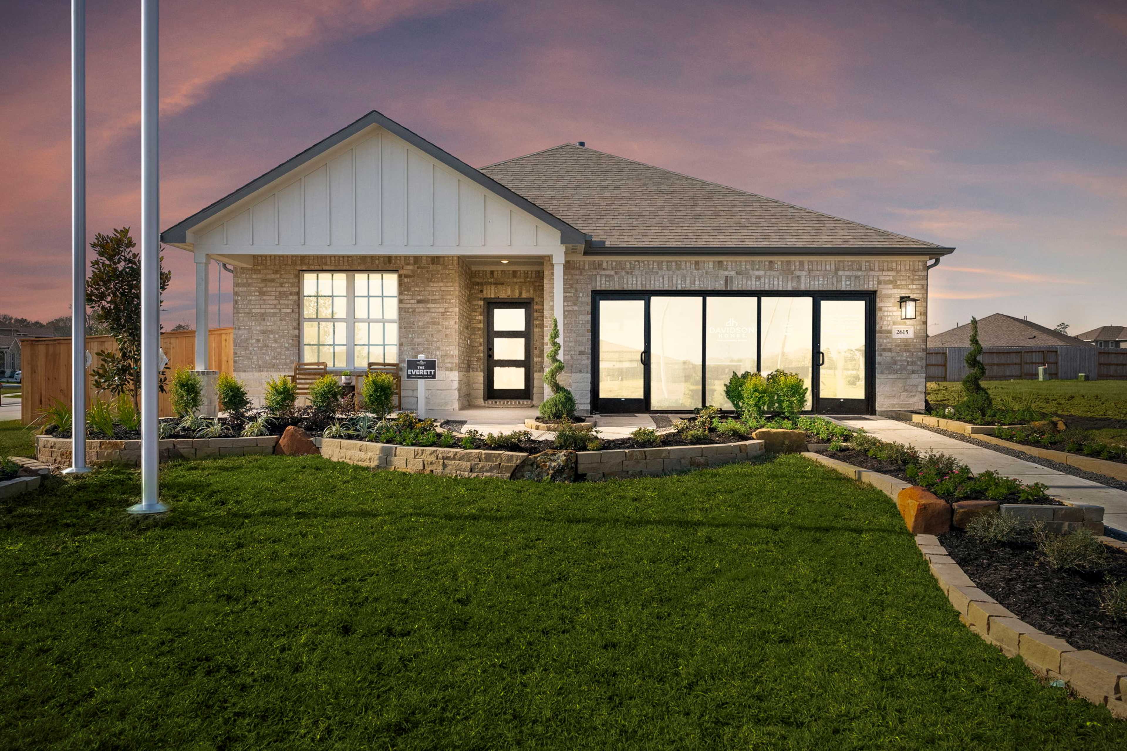 Contemporary home exterior at Sundance Cove in Crosby, Texas with large windows, covered porch, and landscaped yard at dusk