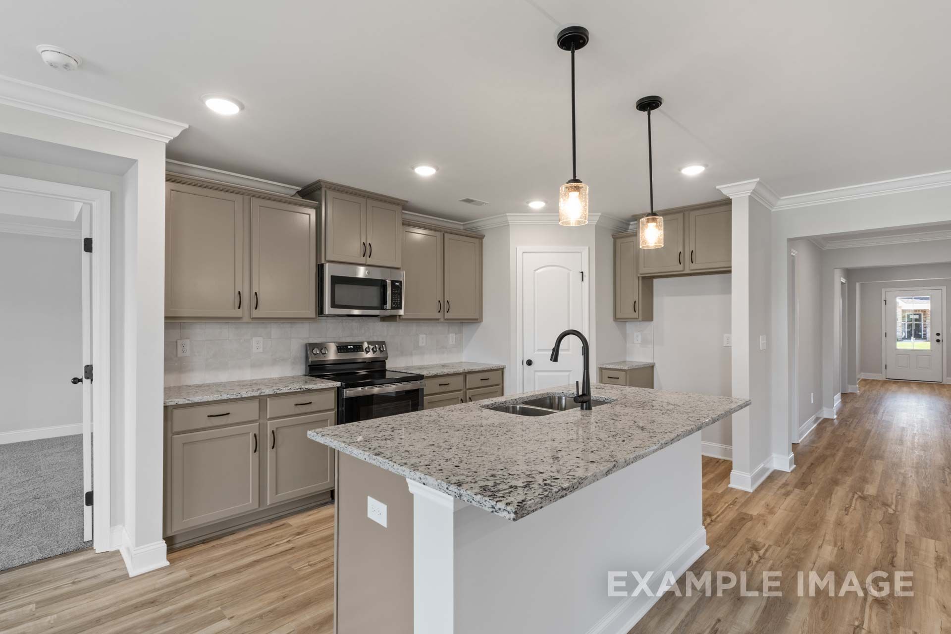 Spacious open-concept kitchen in The Holly M with gray cabinets, granite island, stainless appliances, wood floors