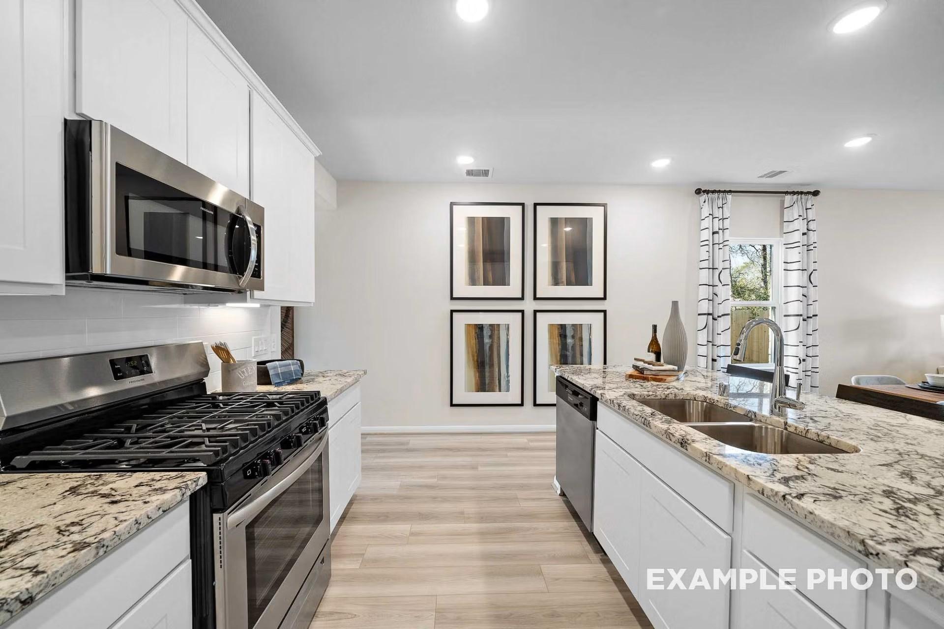 Modern kitchen with white cabinets, granite countertops, and stainless appliances in San Marcos E floor plan, Heartland, TX.