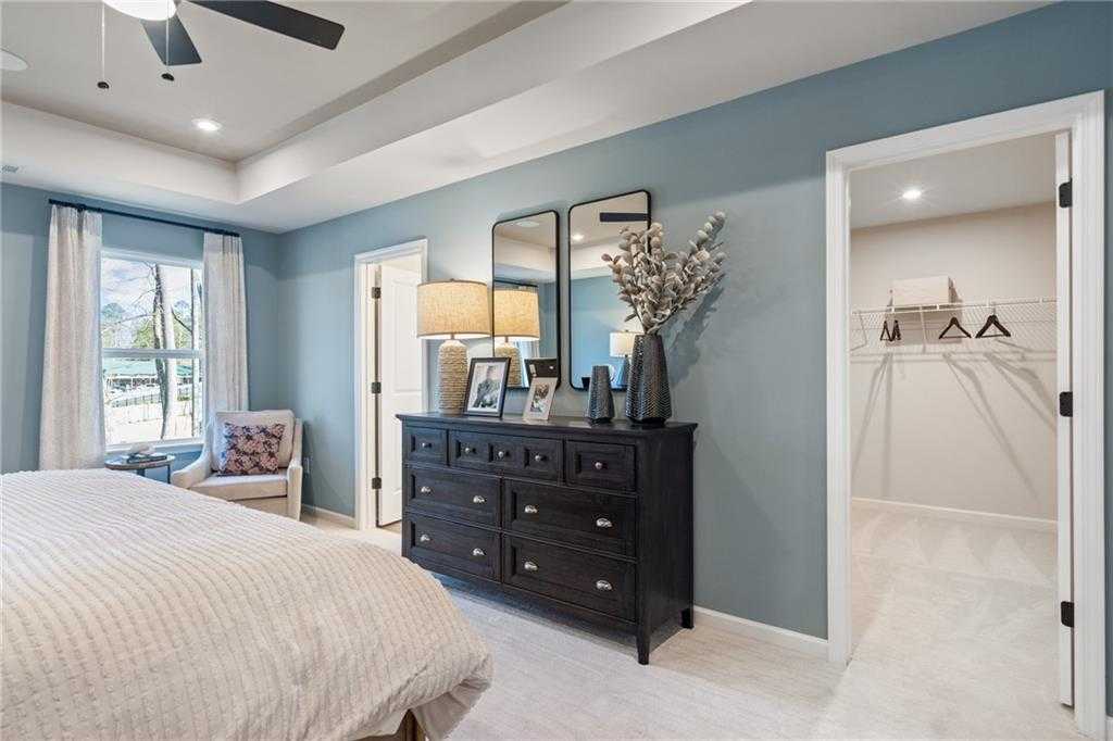 Elegant master bedroom with blue walls, king bed, dresser, and walk-in closet in Davidson Homes The Marion C, Winder, GA