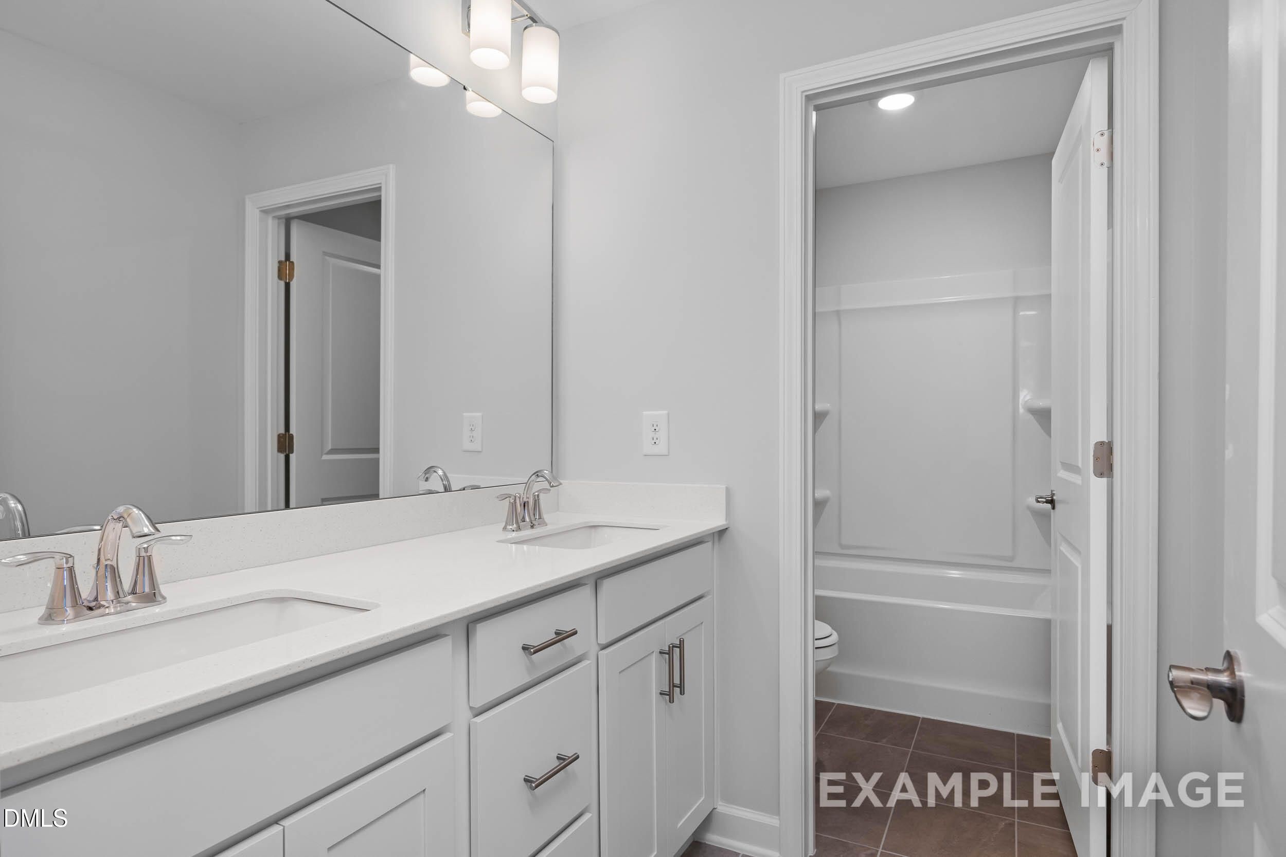 Modern master bathroom with double vanity, soaking tub, and white cabinetry in Davidson Homes The Ash B, Lillington, NC