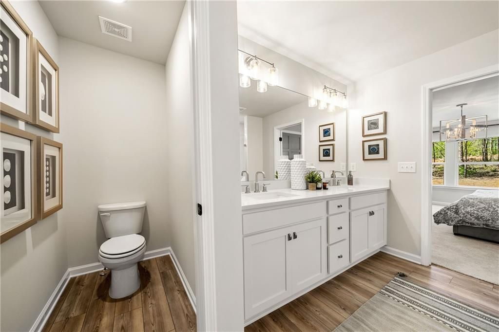 Modern master bathroom with double vanity, lighted mirror, separate toilet room, and bedroom view in Davidson Homes Willow B, Dallas, GA