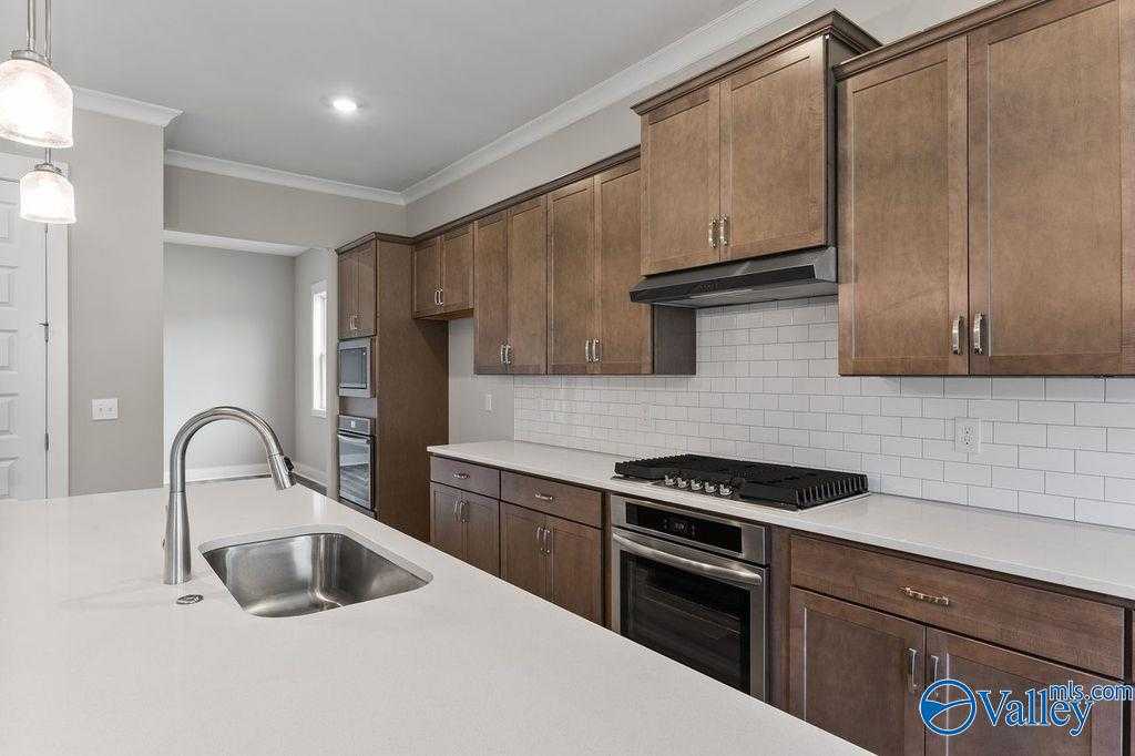 Modern kitchen with white quartz counters, shaker cabinets, stainless appliances in Evermore Homes The Oxford, Owens Cross Roads, AL