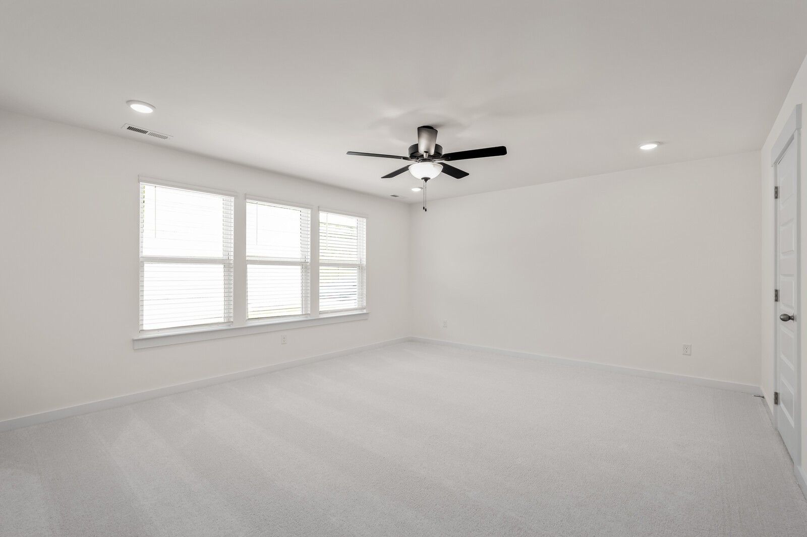 Bright, spacious bedroom with neutral carpet and ceiling fan in The Willow floor plan by Davidson Homes in Gallatin, TN.