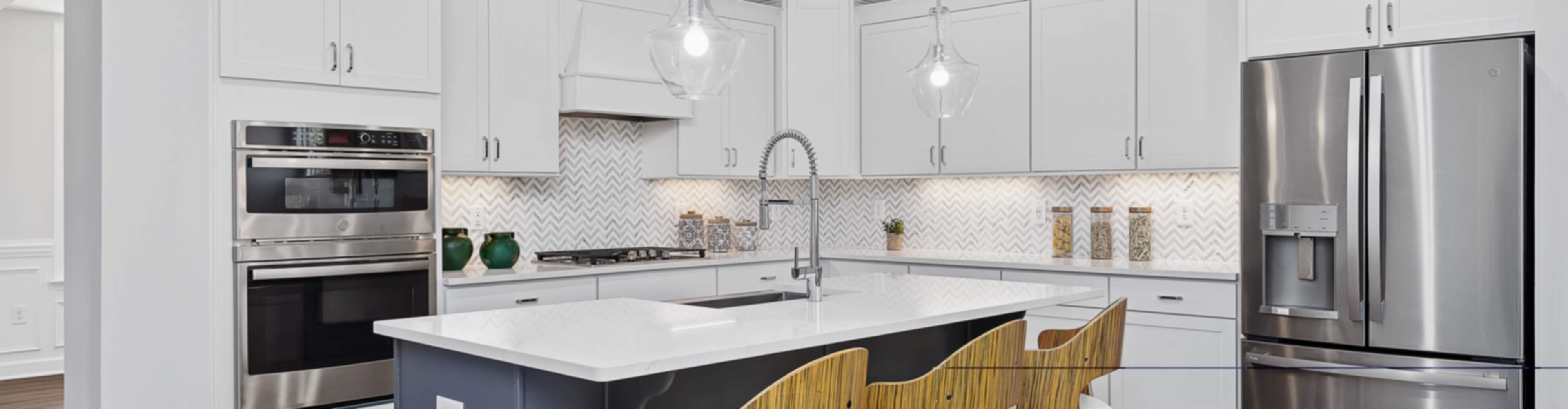 Spacious modern kitchen in a Mooresville home with white cabinets, blue island, bar stools, and stainless appliances