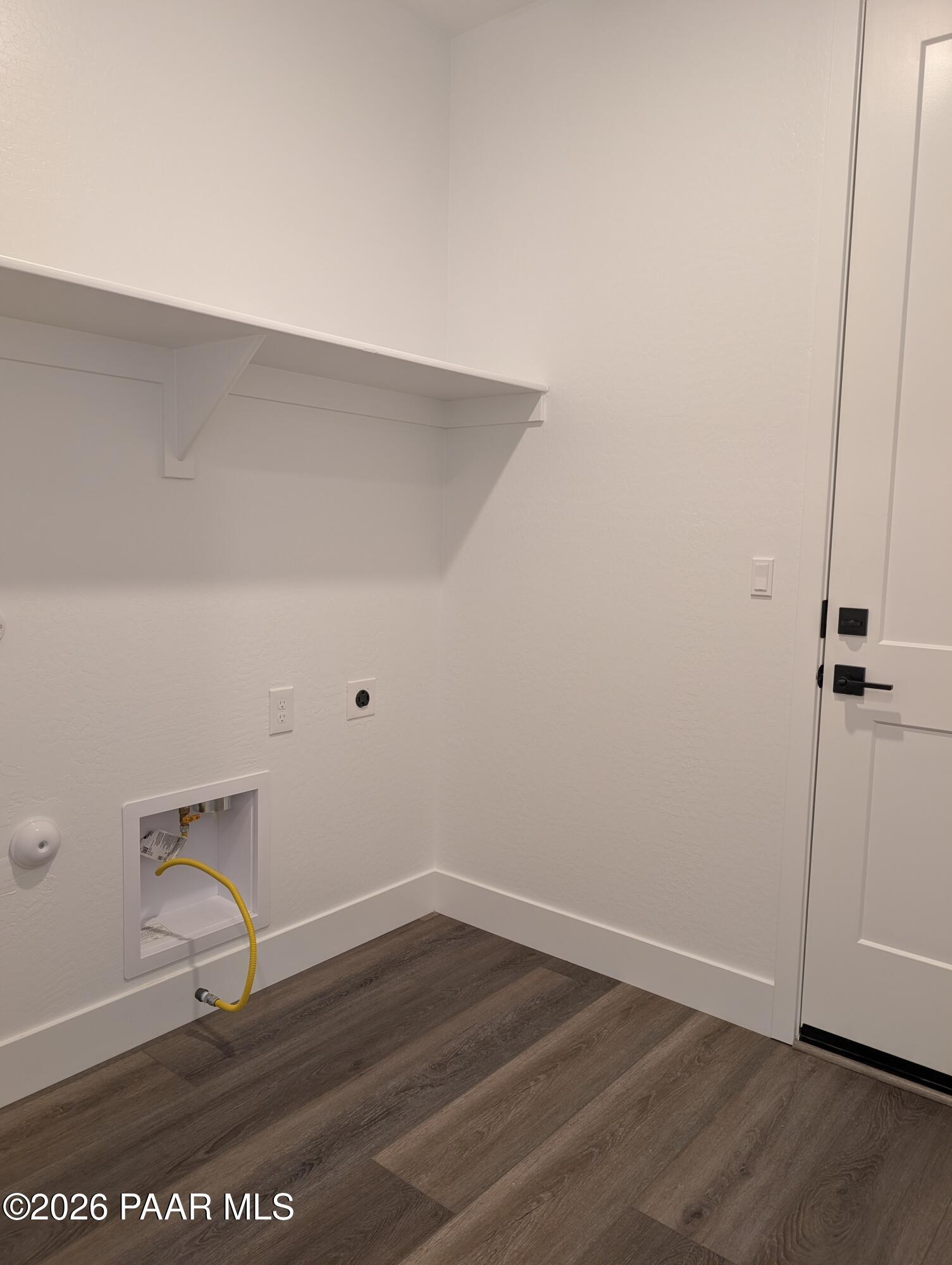 Spacious laundry room with built-in white shelves, washer-dryer hookups and wood flooring in Davidson Homes The Sheridan II G, Prescott, Arizona