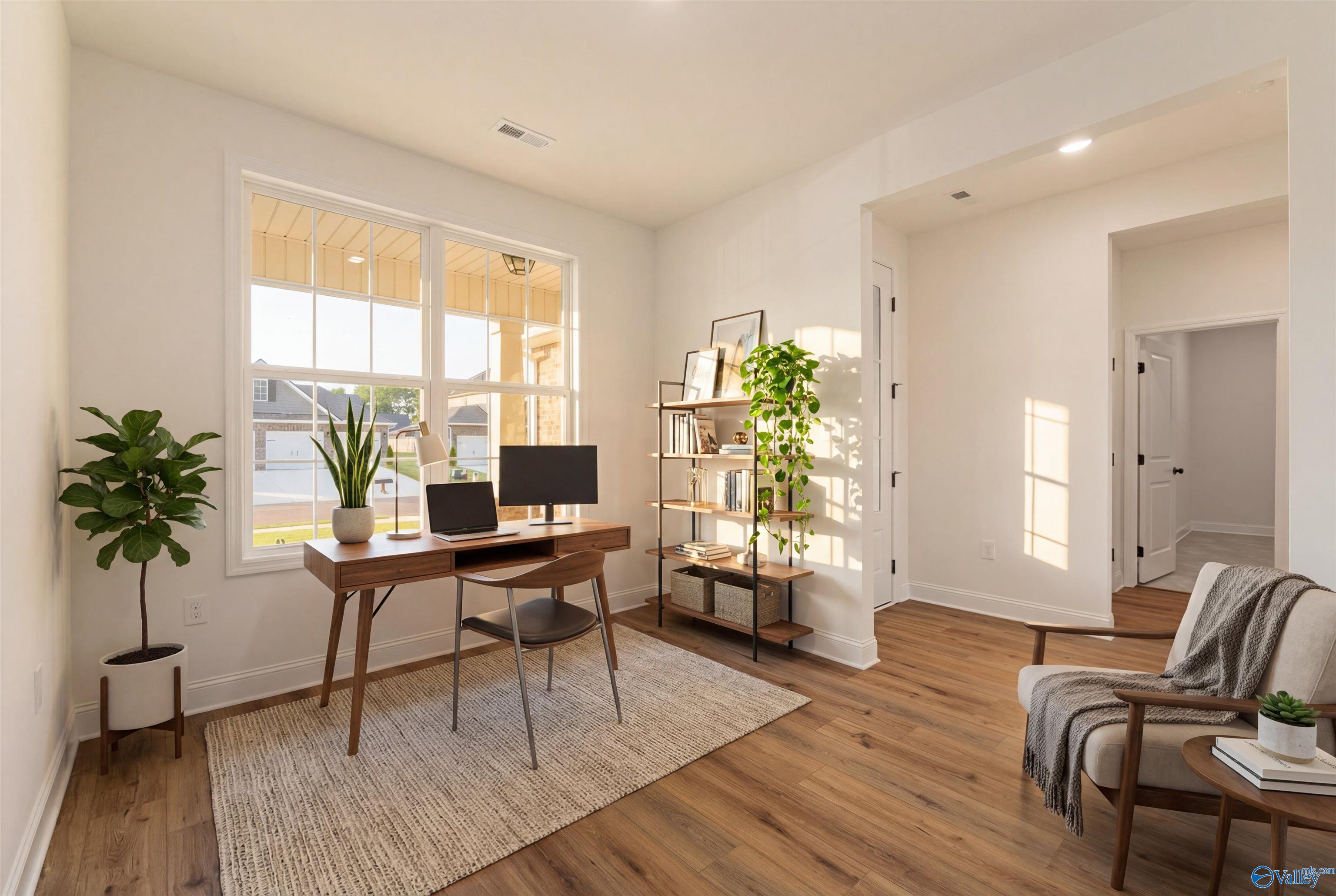 Sunlit home office with wooden desk, potted plants, bookshelf, and natural light in Davidson Homes The Rockford B, Toney, Alabama
