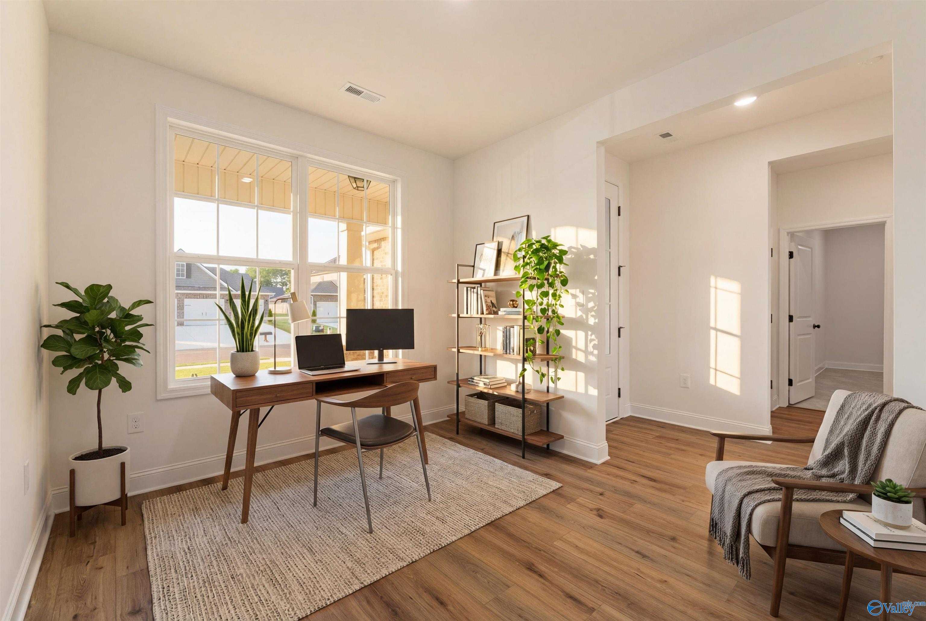 Sunlit home office with wooden desk, potted plants, bookshelf, and natural light in Davidson Homes The Rockford B, Toney, Alabama