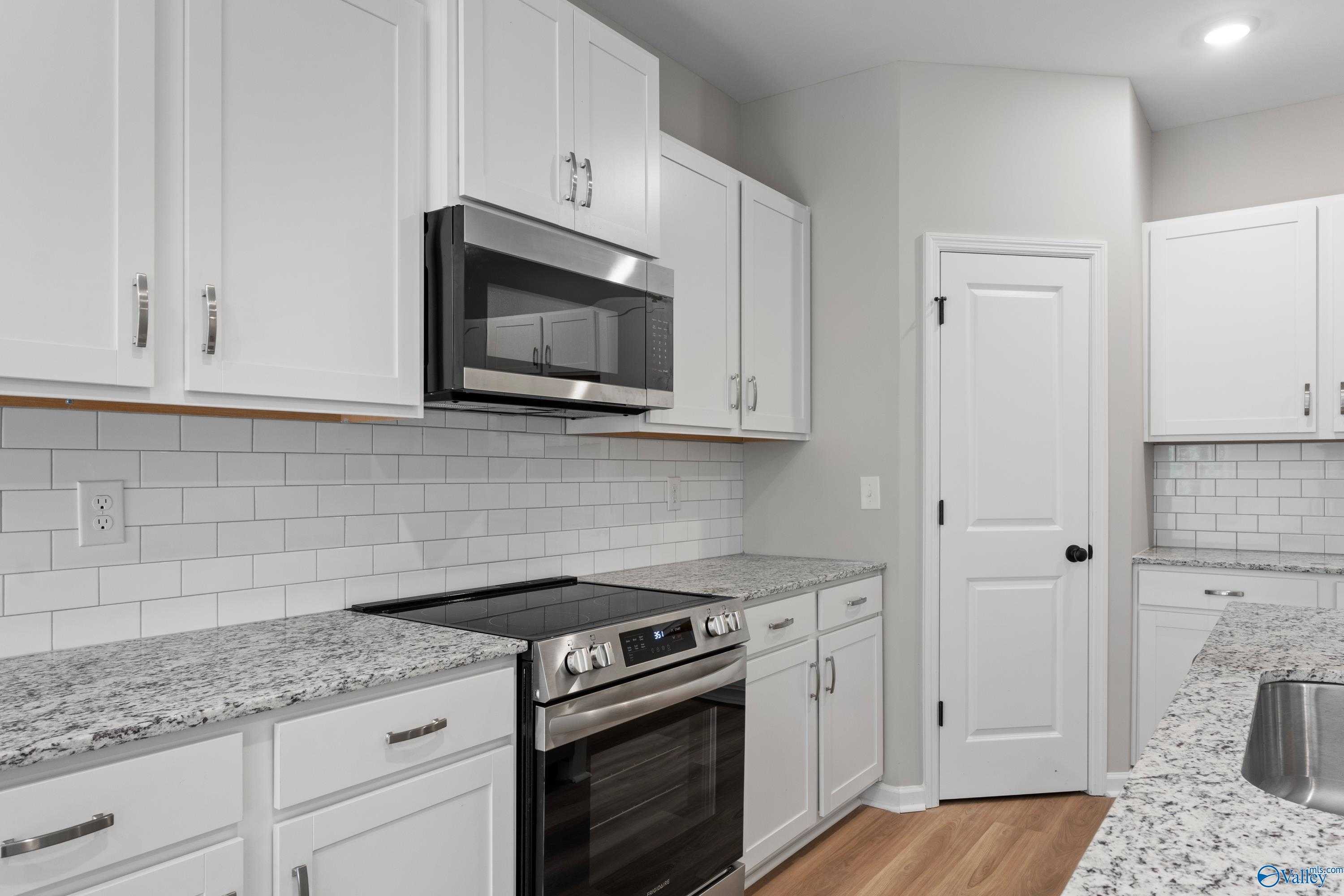 Modern kitchen with white shaker cabinets, granite countertops, stainless appliances, subway tile in Davidson Homes The Phoenix, Fayetteville, TN