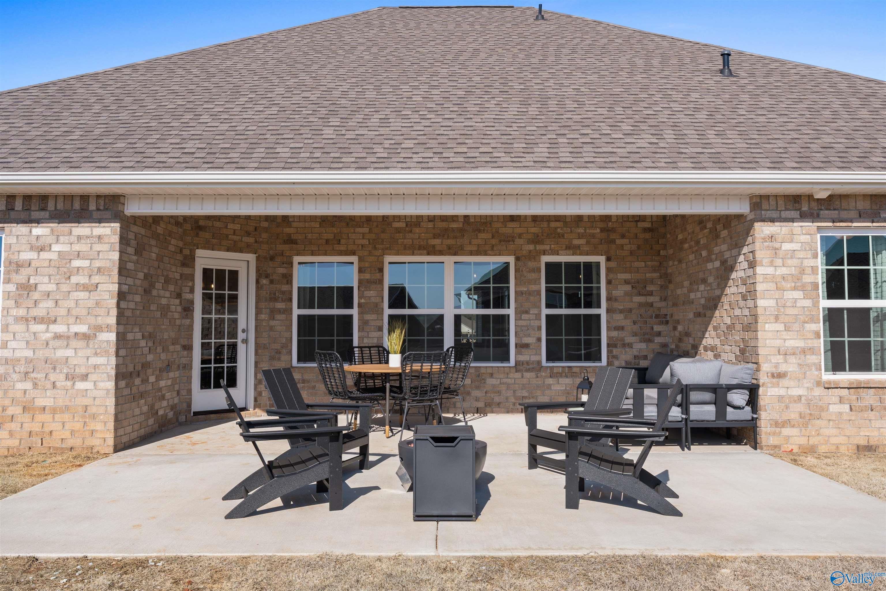 Covered back patio with Adirondack chairs, fire pit, and sofa in Davidson Homes The Rockford B, Madison, Alabama