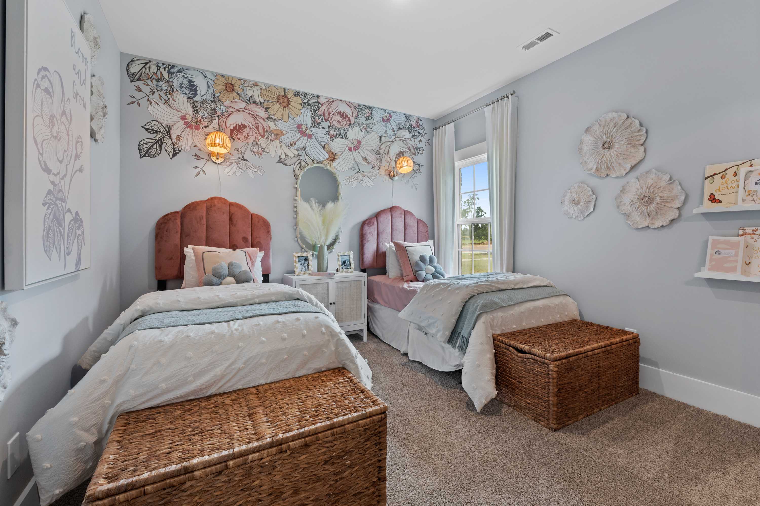 Charming girls' twin bedroom at Creekside in Harvest, Alabama with floral wallpaper, pink tufted headboards, and wicker baskets
