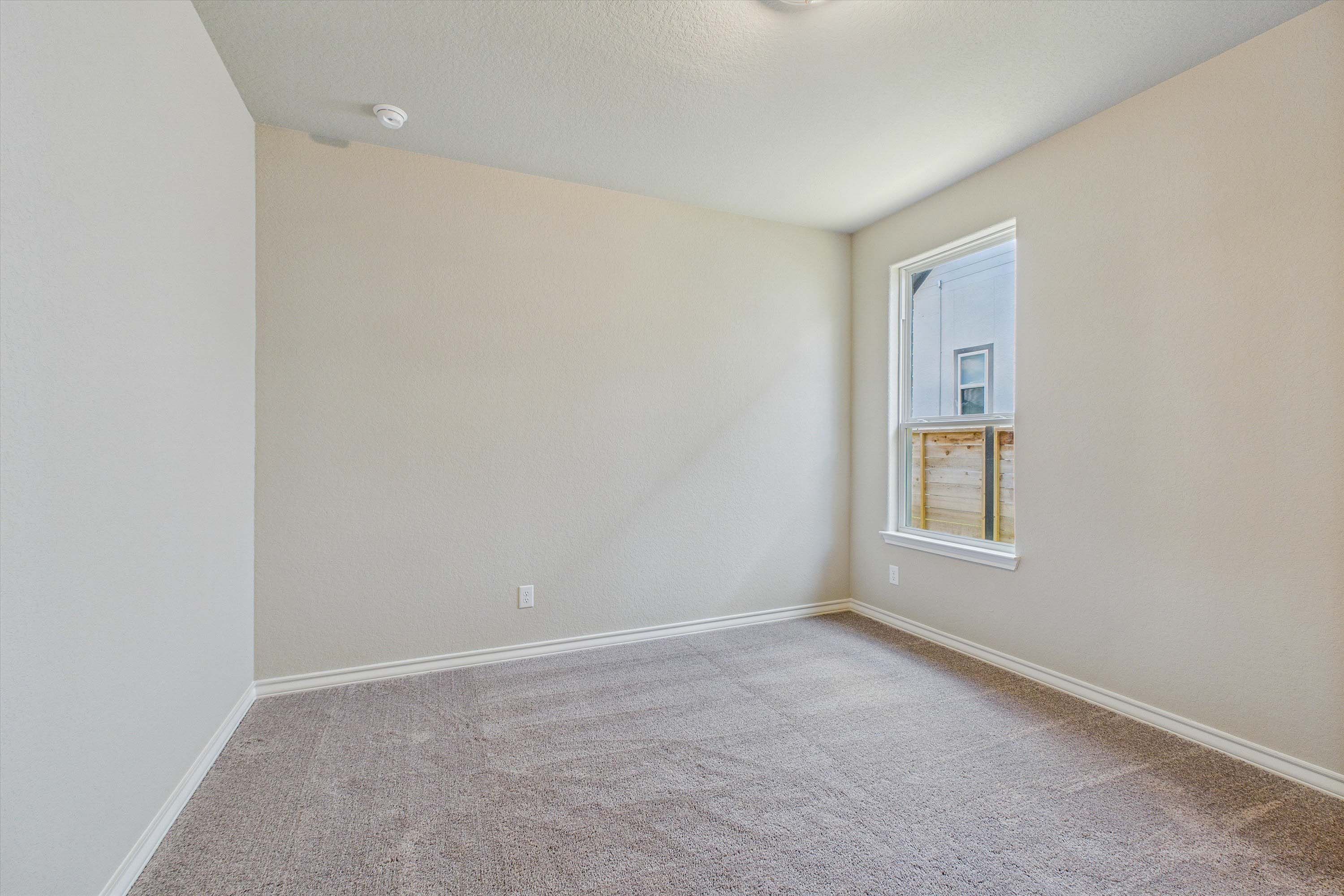 Spacious, carpeted bedroom in The Foster home design by Davidson Homes featuring neutral walls and natural light.