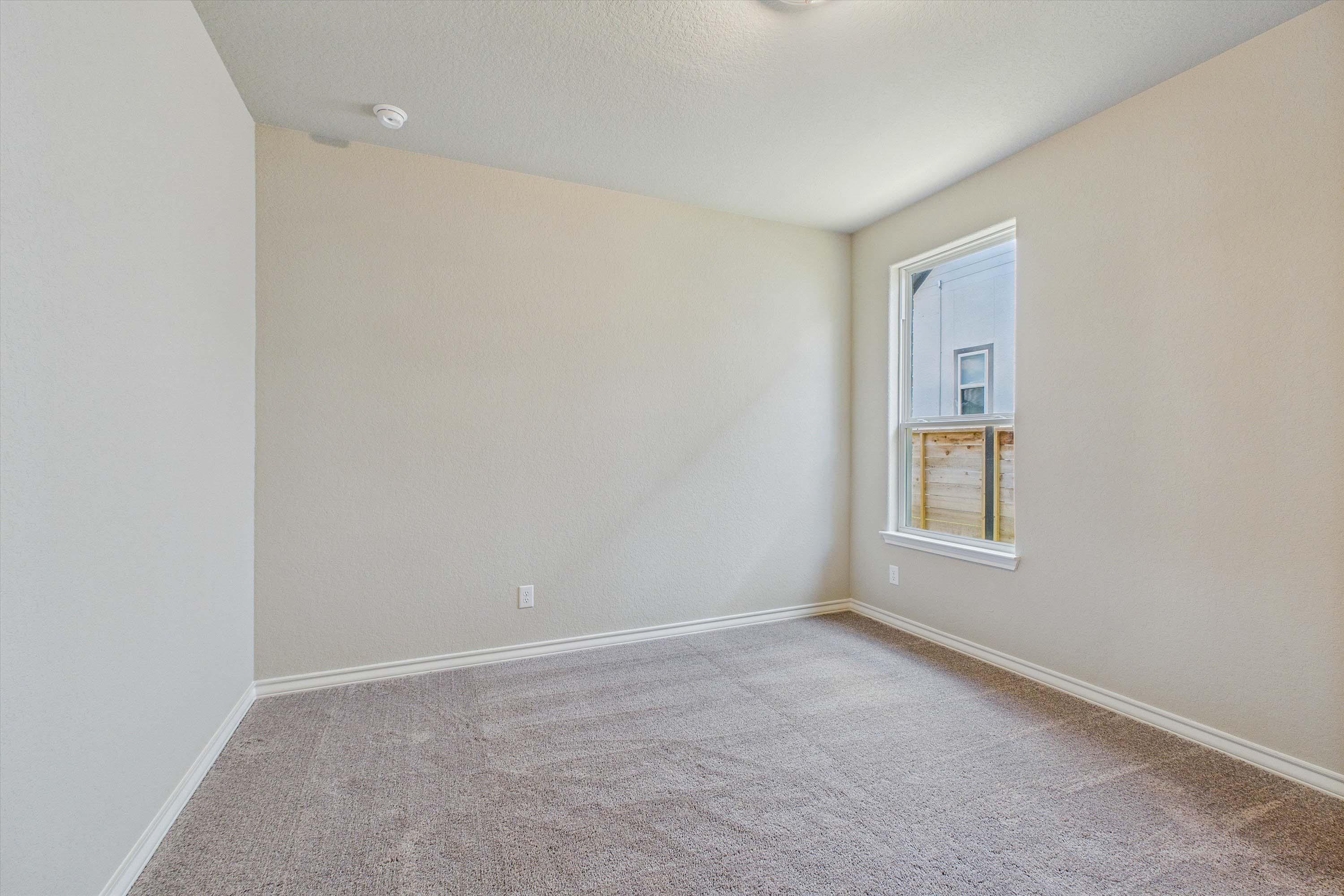 Spacious, carpeted bedroom in The Foster home design by Davidson Homes featuring neutral walls and natural light.