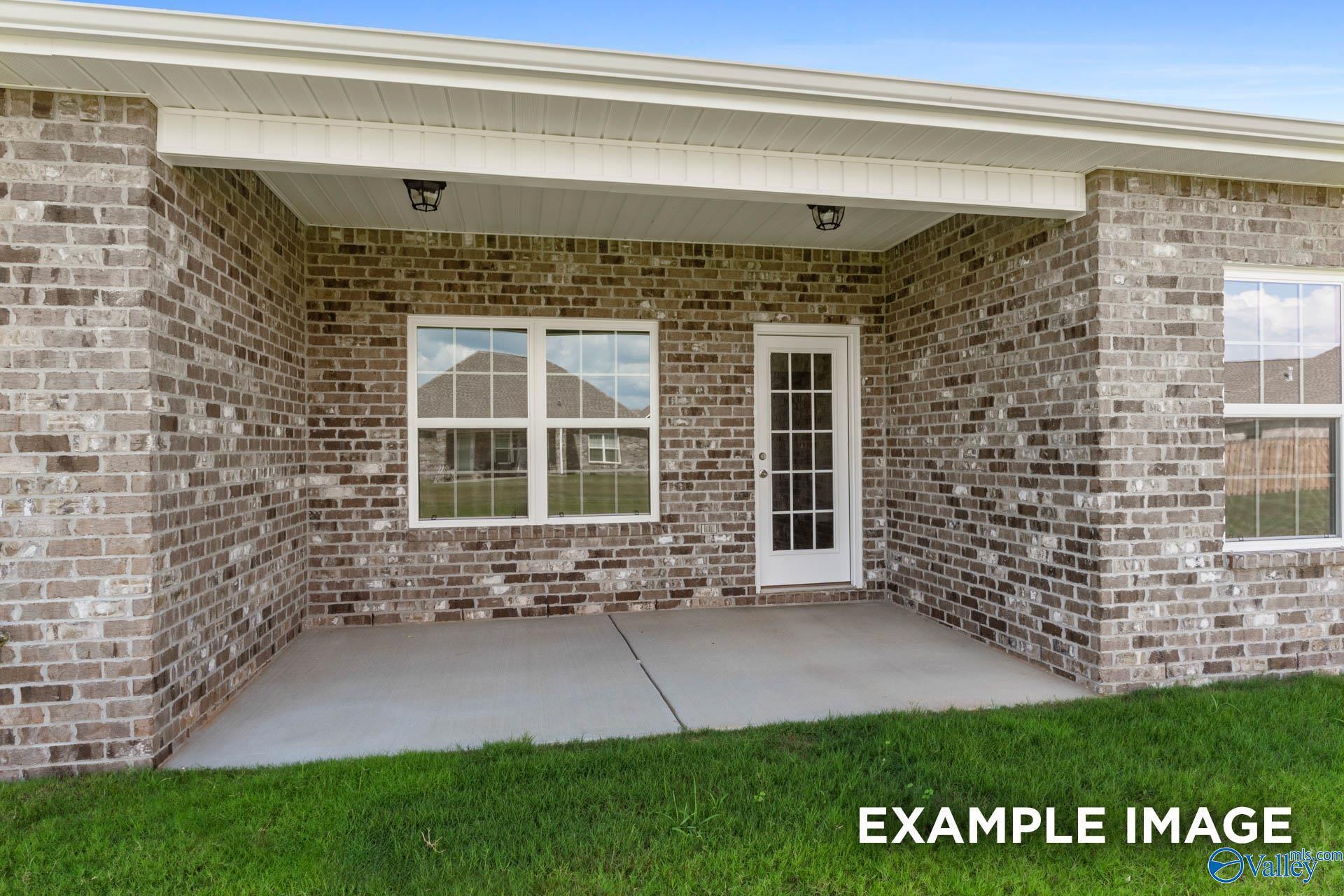 Covered brick patio with French door and double windows on single-story Davidson Homes Montgomery B in Hartselle, Alabama