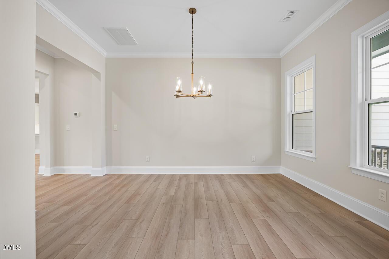 Bright dining room with brass chandelier, luxury vinyl plank flooring, and oversized windows in Davidson Homes Crawford D plan, Wake Forest, NC