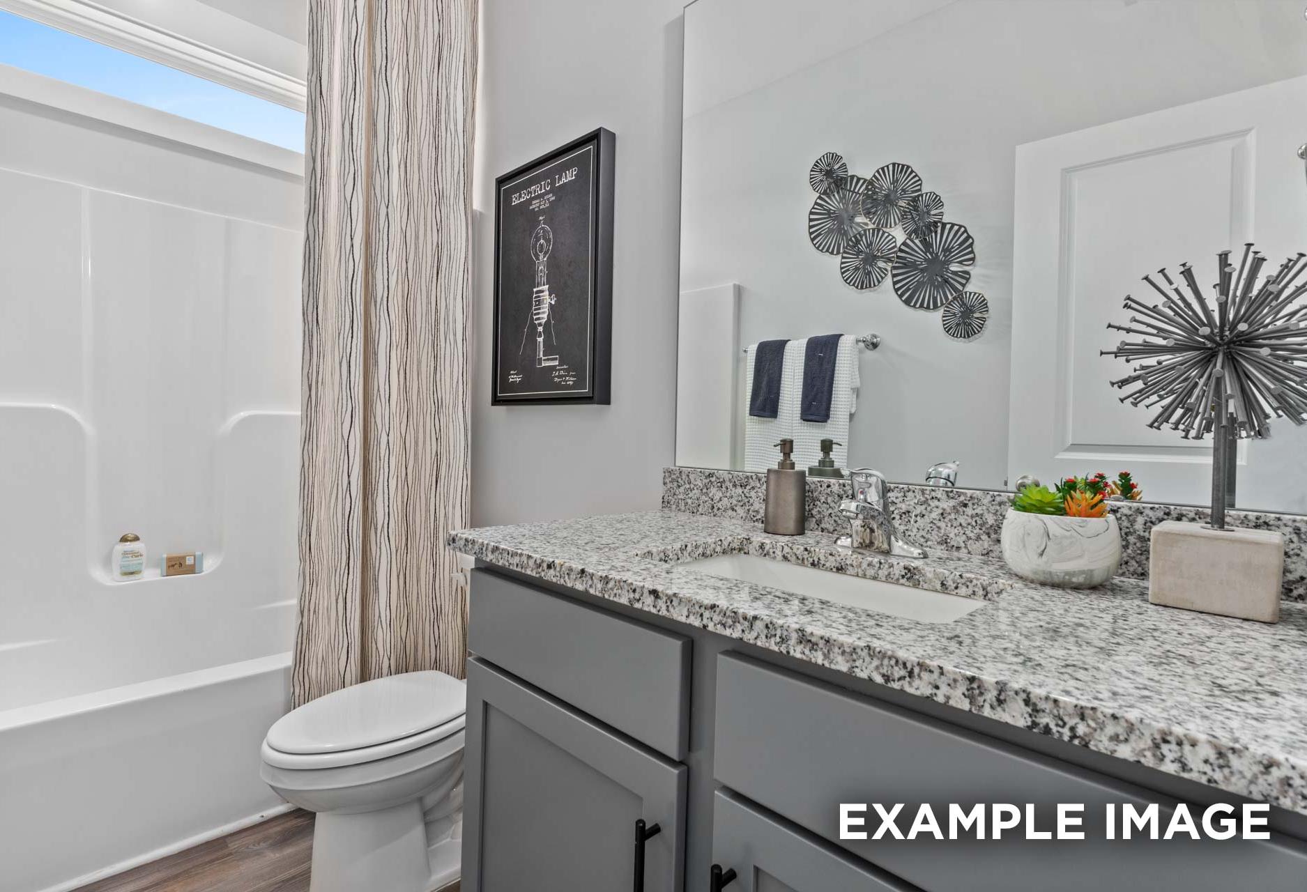 Spacious master bathroom in The Franklin C featuring granite countertop, soaking tub, walk-in shower, and modern accents