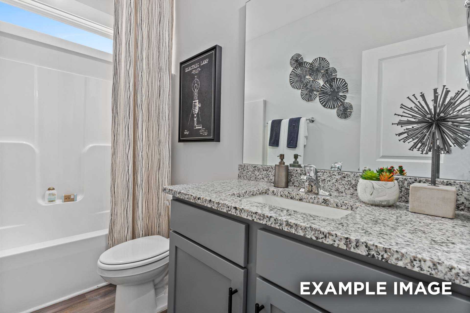 Spacious master bathroom in The Franklin C featuring granite countertop, soaking tub, walk-in shower, and modern accents