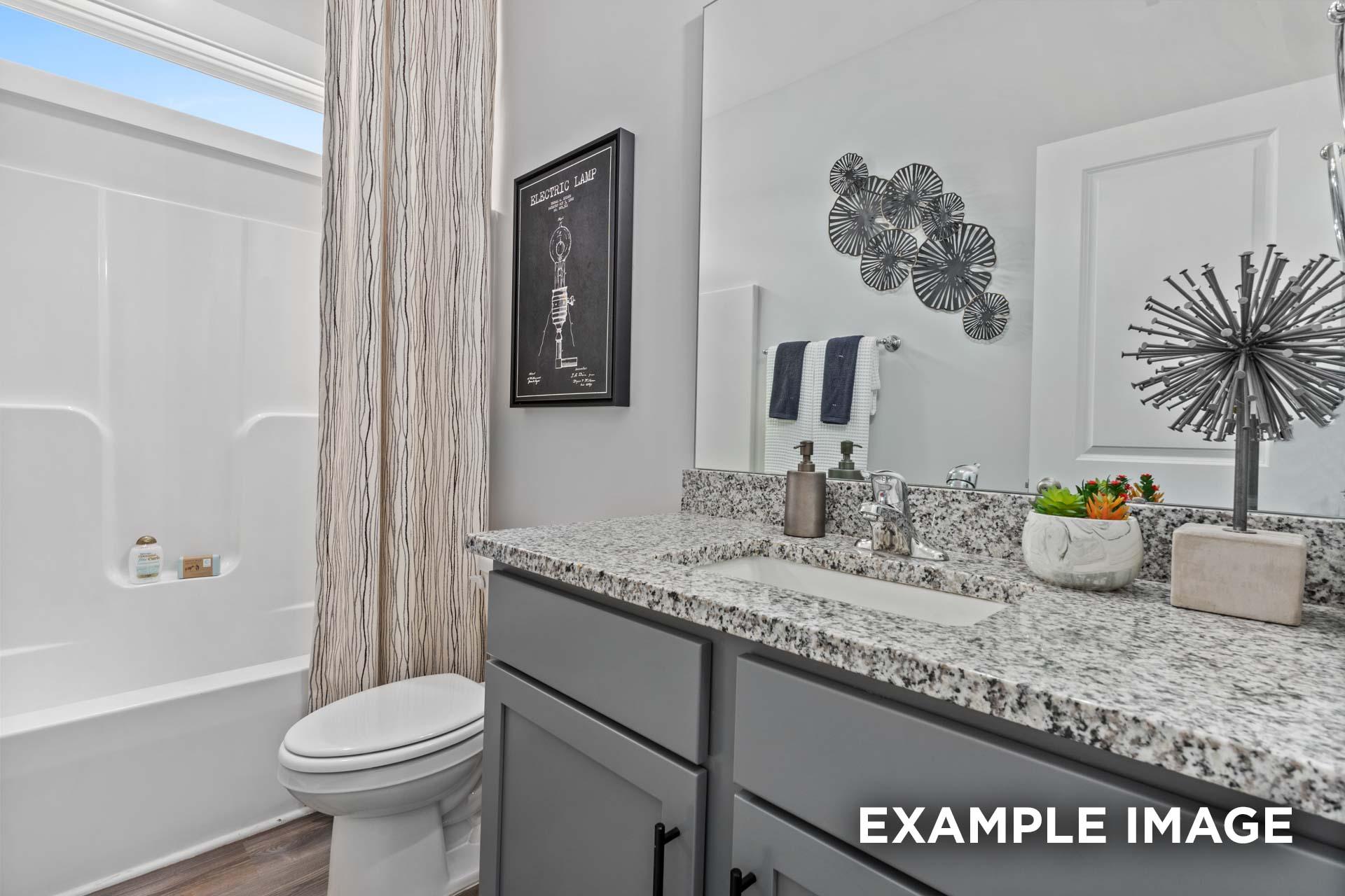 Spacious master bathroom in The Franklin C featuring granite countertop, soaking tub, walk-in shower, and modern accents