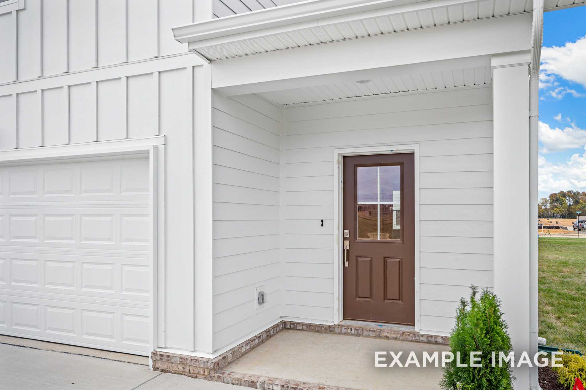 Front elevation of The Grayson B showcasing white board-and-batten siding, covered porch with columns, and 2-car garage