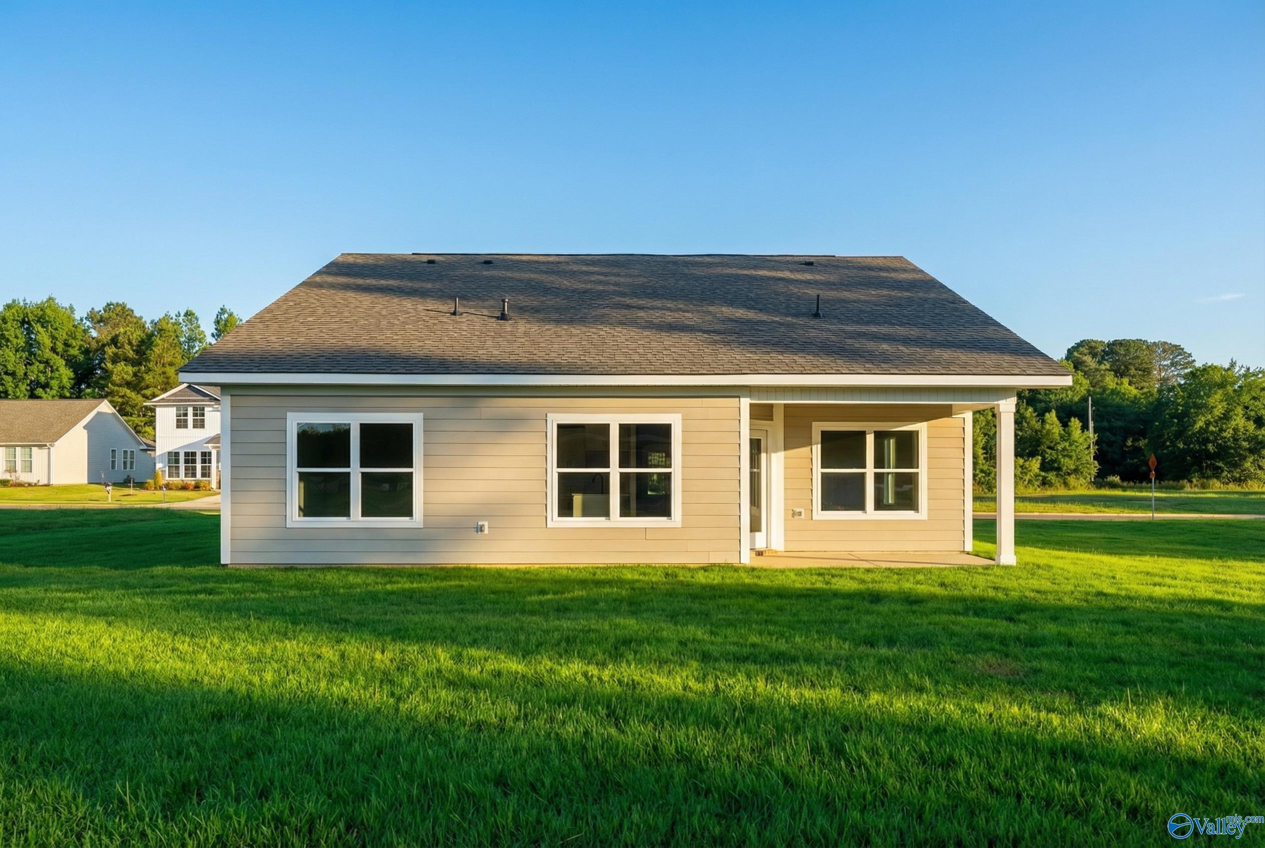 Single-story tan Franklin E home by Davidson Homes in Forest Glen, Hazel Green, Alabama, with front porch, large windows, and lush green lawn