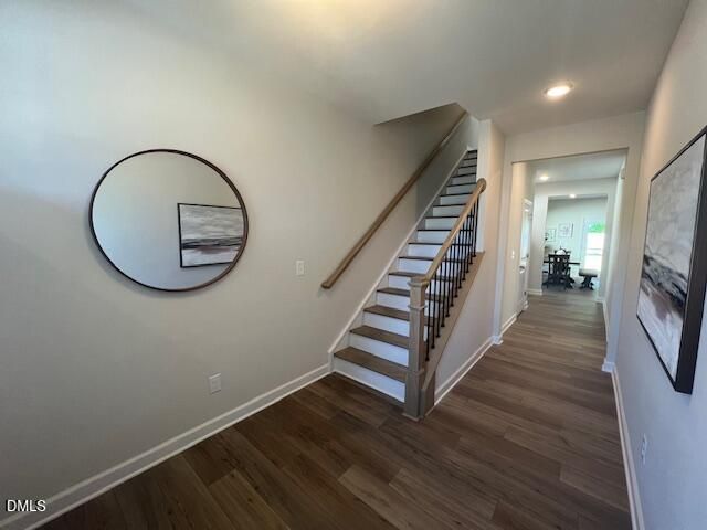Elegant foyer with hardwood floors, wooden staircase, round mirror, and abstract wall art in 4-bedroom Preston A home, Lillington, NC