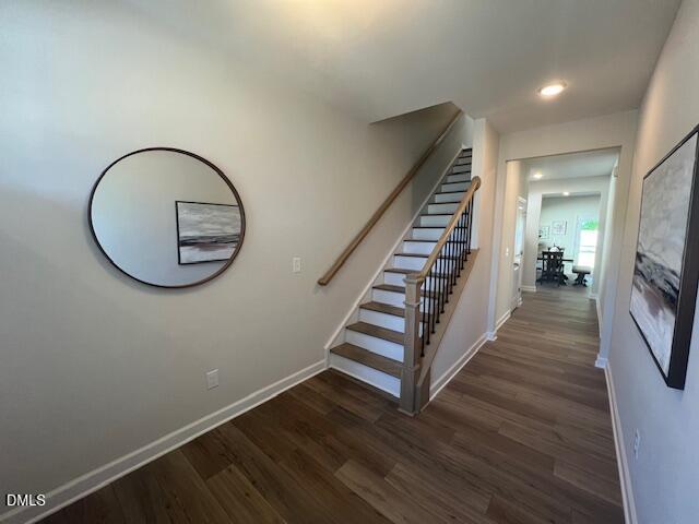 Elegant foyer with hardwood floors, wooden staircase, round mirror, and abstract wall art in 4-bedroom Preston A home, Lillington, NC