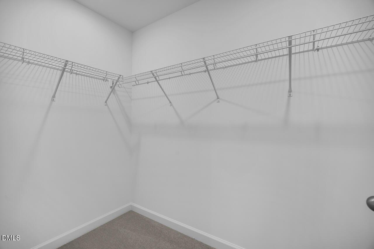 Spacious walk-in closet featuring wire shelving and hanging rods in Davidson Homes The Avery, Knightdale, NC