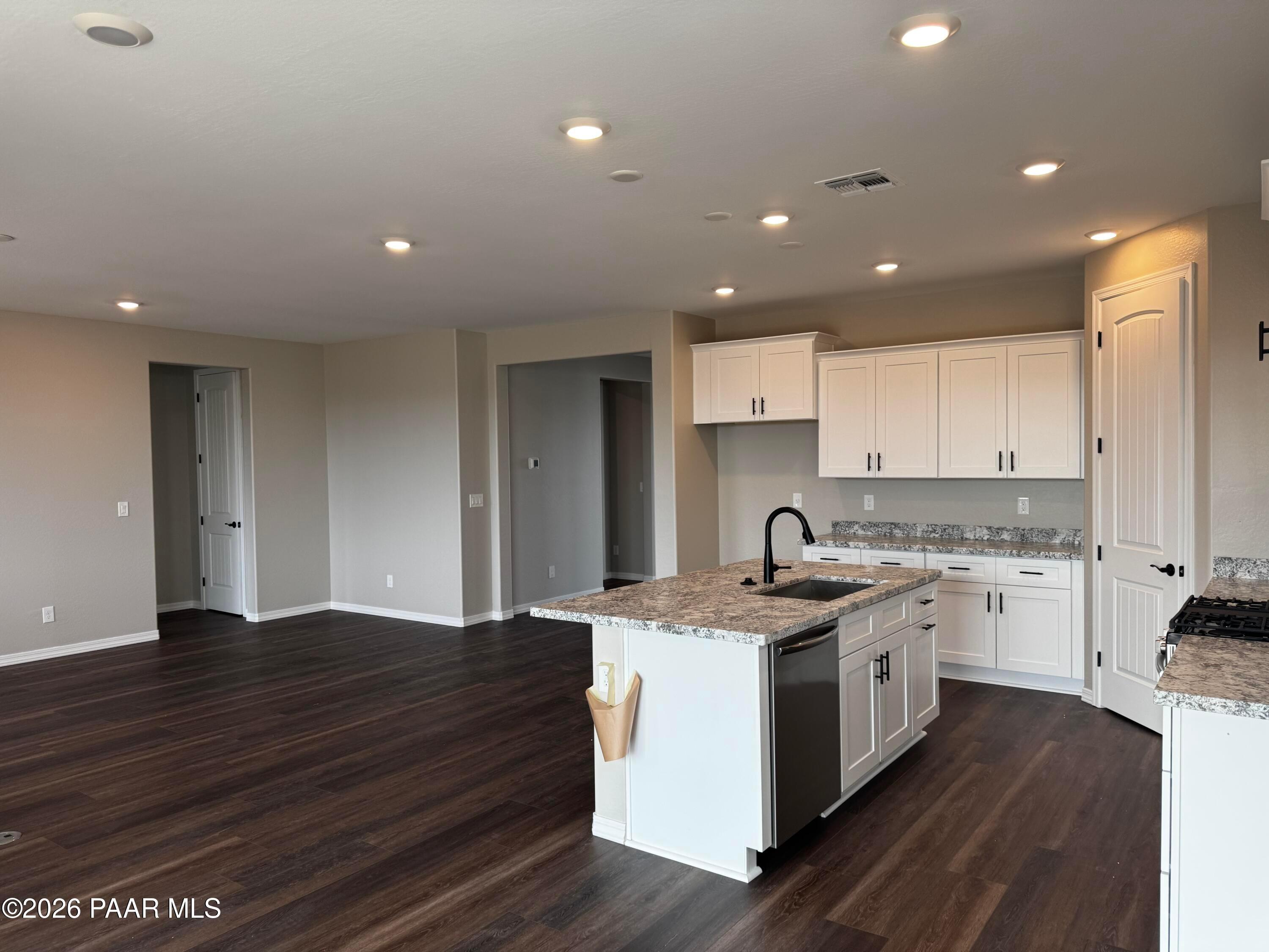 Modern kitchen with granite island, white cabinets, stainless appliances, and open layout in Durango II B home, Prescott, AZ