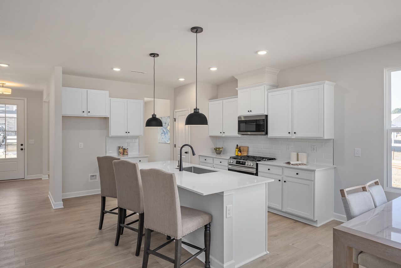 Modern kitchen with white cabinets, quartz island, and pendant lighting at Retreat at North Main in Lillington, NC.