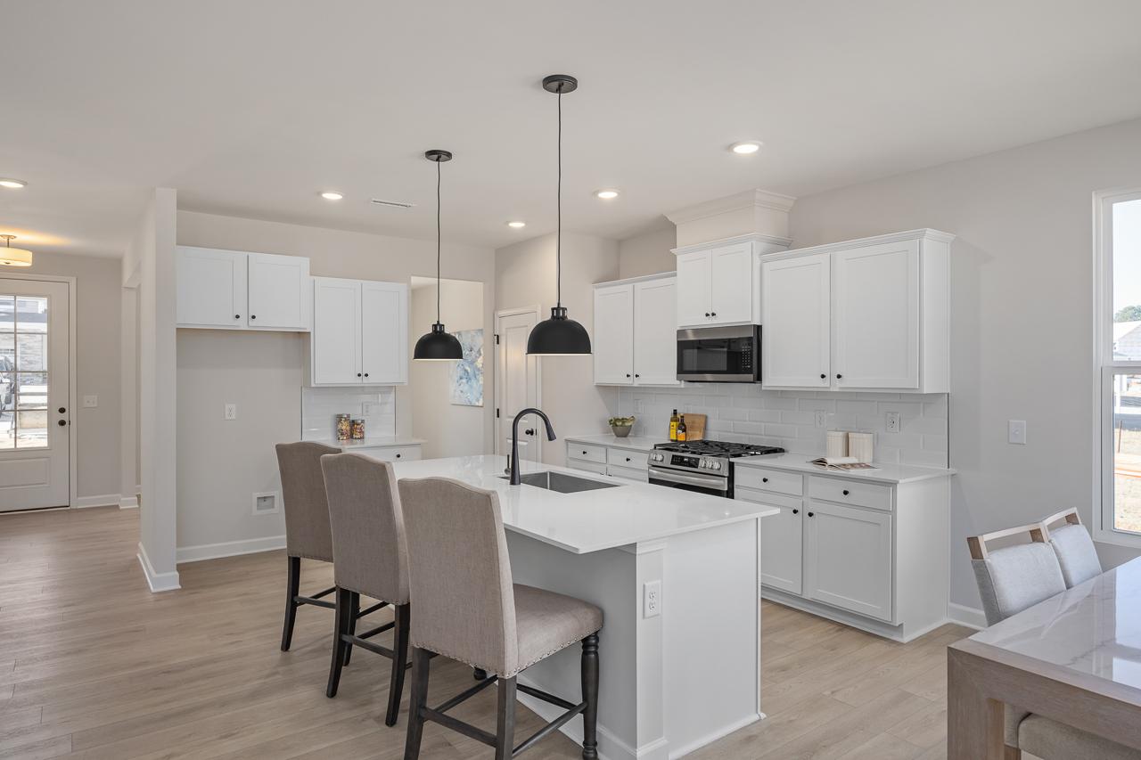 Modern kitchen with white cabinets, quartz island, and pendant lighting at Retreat at North Main in Lillington, NC.