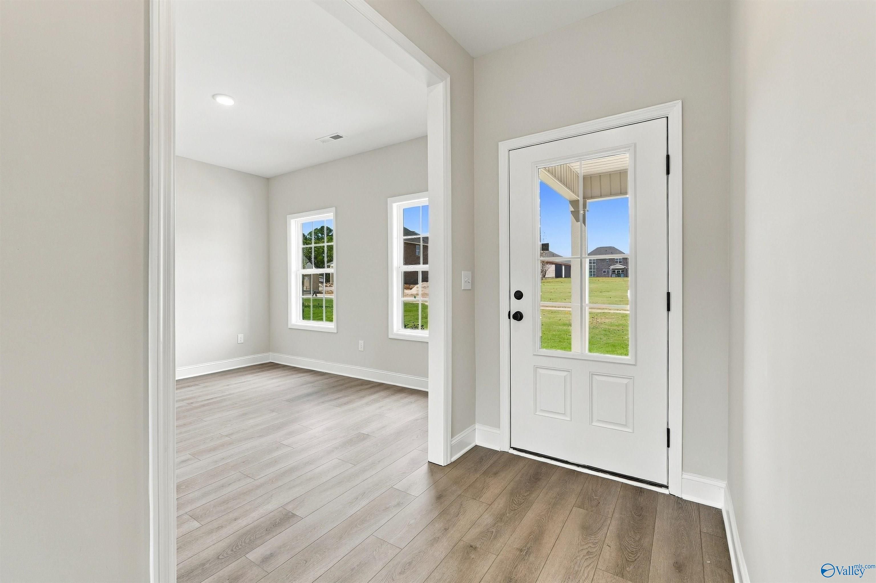 Bright entryway with glass-panel white front door and luxury vinyl plank flooring in Davidson Homes' The Shelby A, Athens, AL.