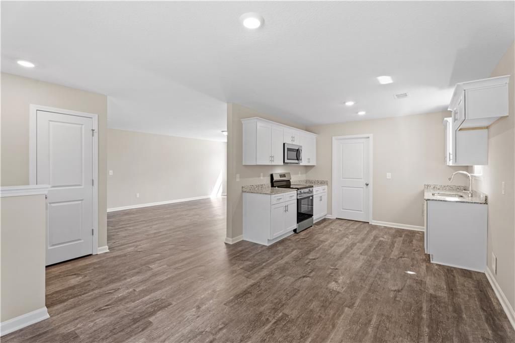 Modern kitchen with white cabinets, stainless steel appliances, and open layout in Davidson Homes The Washington, Phenix City, AL