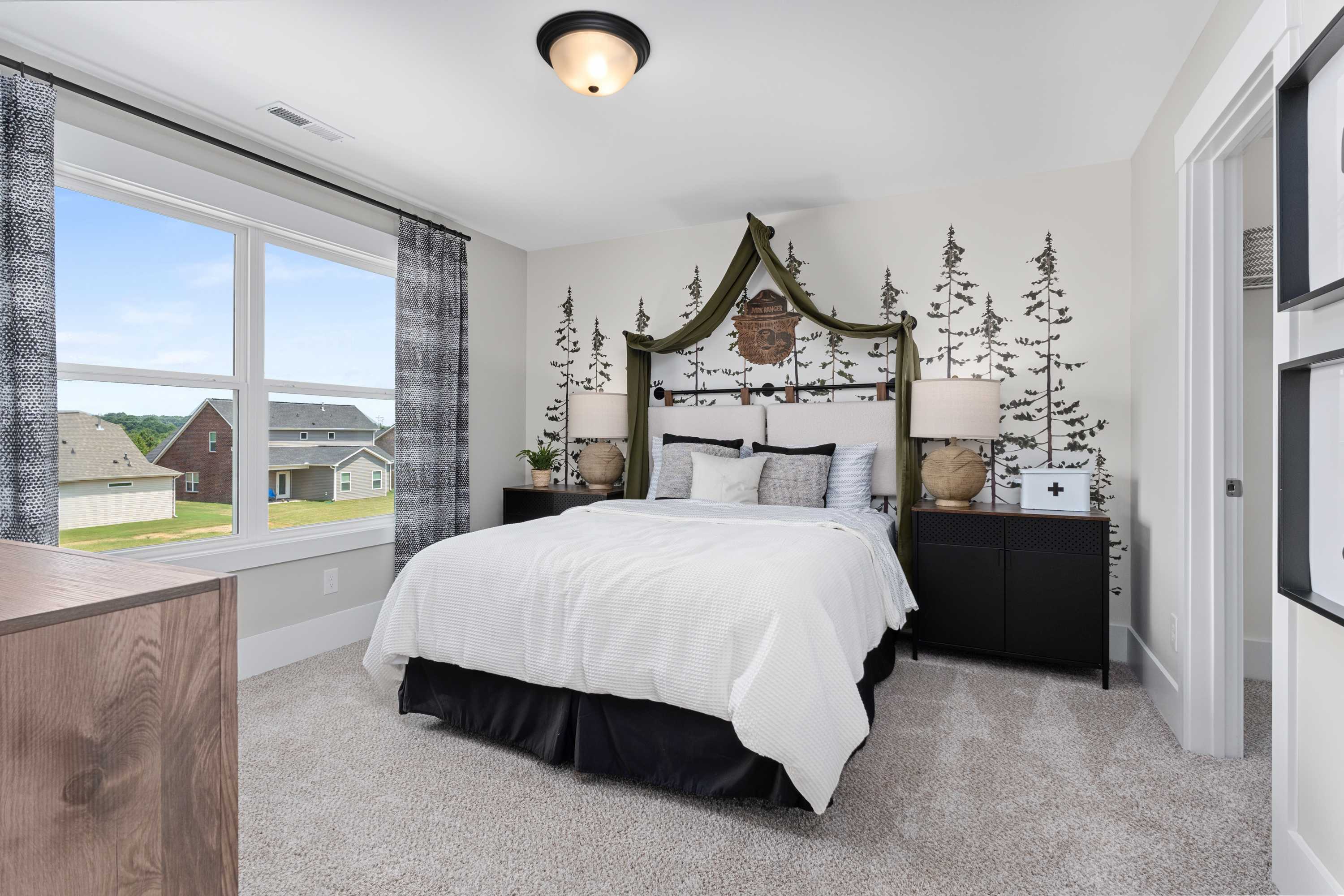 Spacious master bedroom in Shelby A home featuring woodland tree wall mural, king bed, and large window view