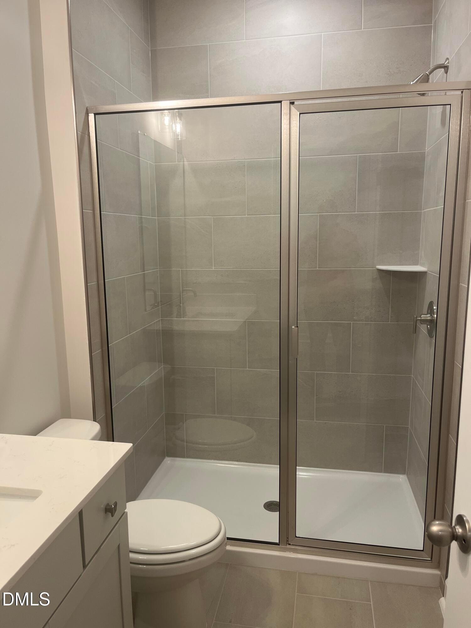 Modern primary bathroom with frameless glass shower, gray subway tiles, quartz vanity in Davidson Homes The Ashport G, Wake Forest, NC