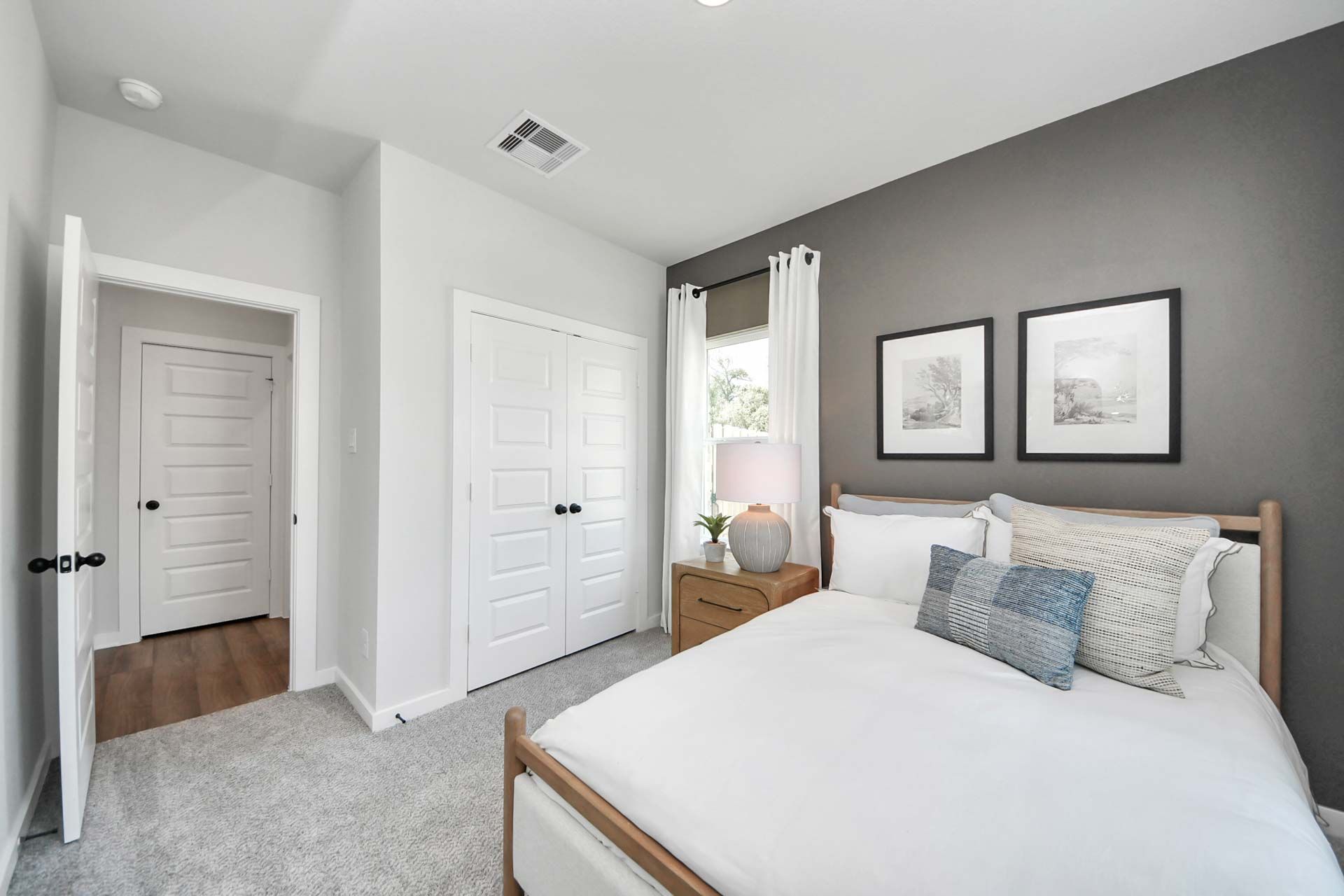 Cozy bedroom with gray accent wall and wood bed frame at Enclave at Newport in Crosby, TX by Davidson Homes.