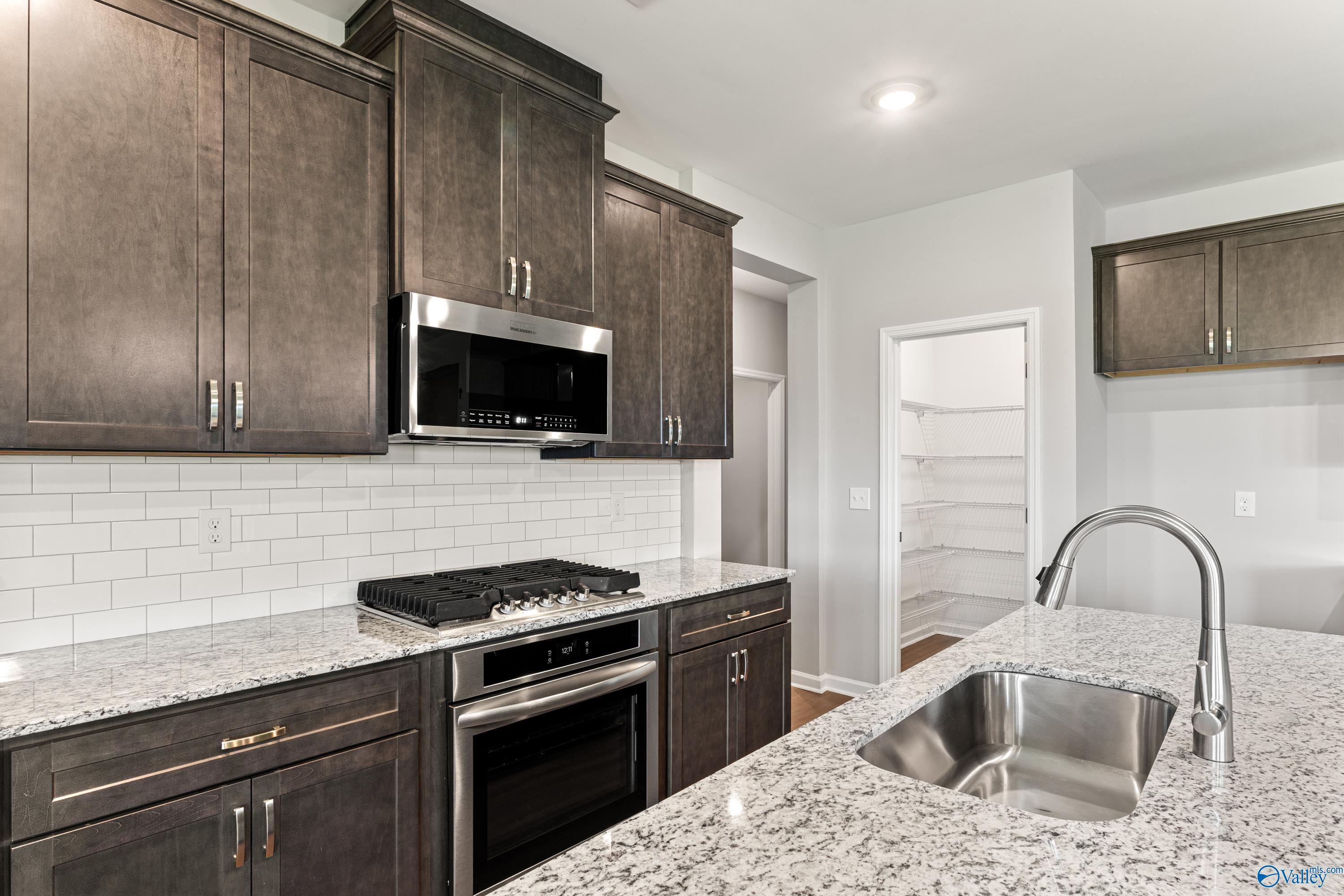 Modern kitchen featuring shaker cabinets, granite counters, stainless appliances in Davidson Homes The Sanctuary, Huntsville AL