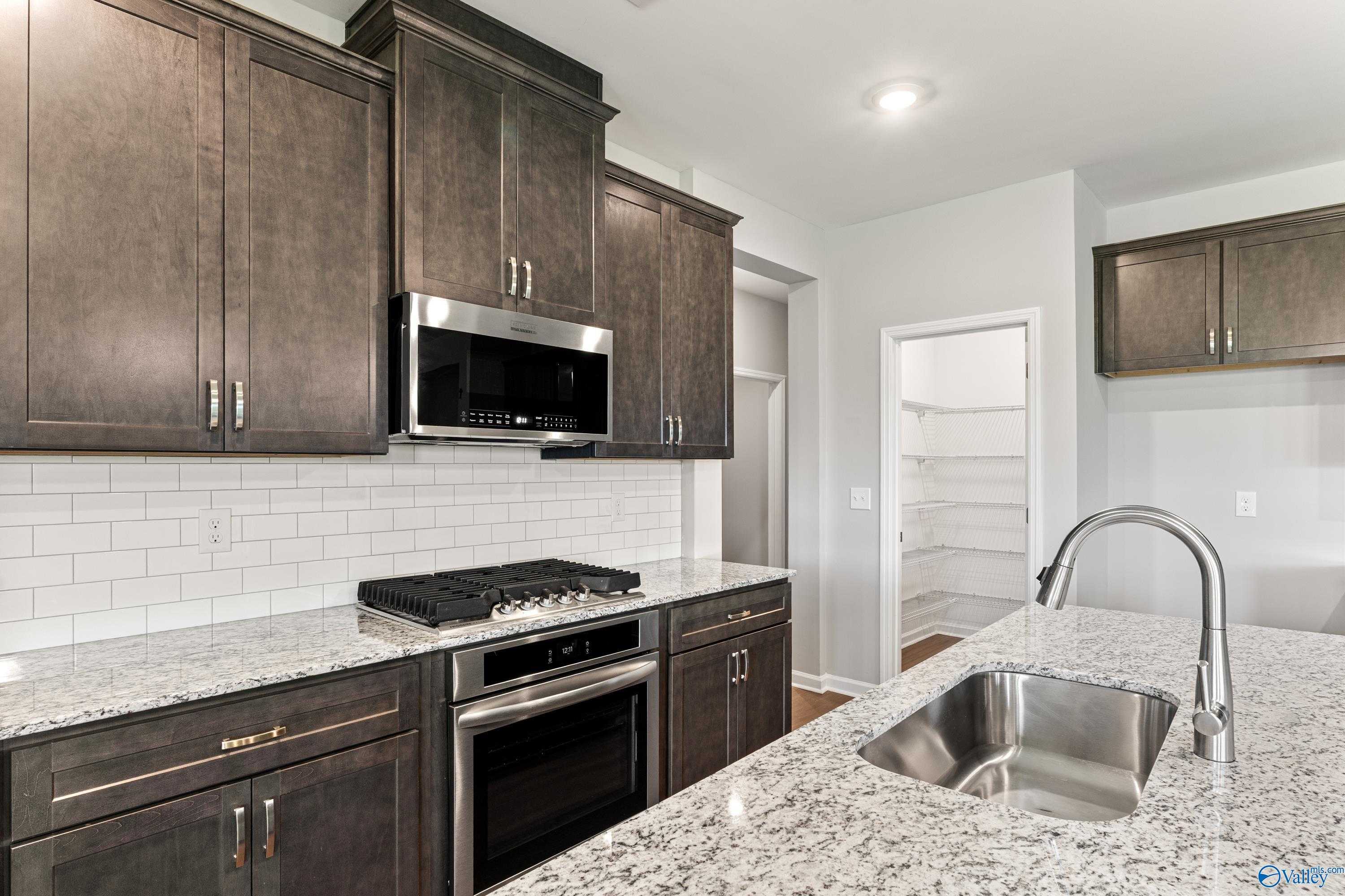 Modern kitchen featuring shaker cabinets, granite counters, stainless appliances in Davidson Homes The Sanctuary, Huntsville AL