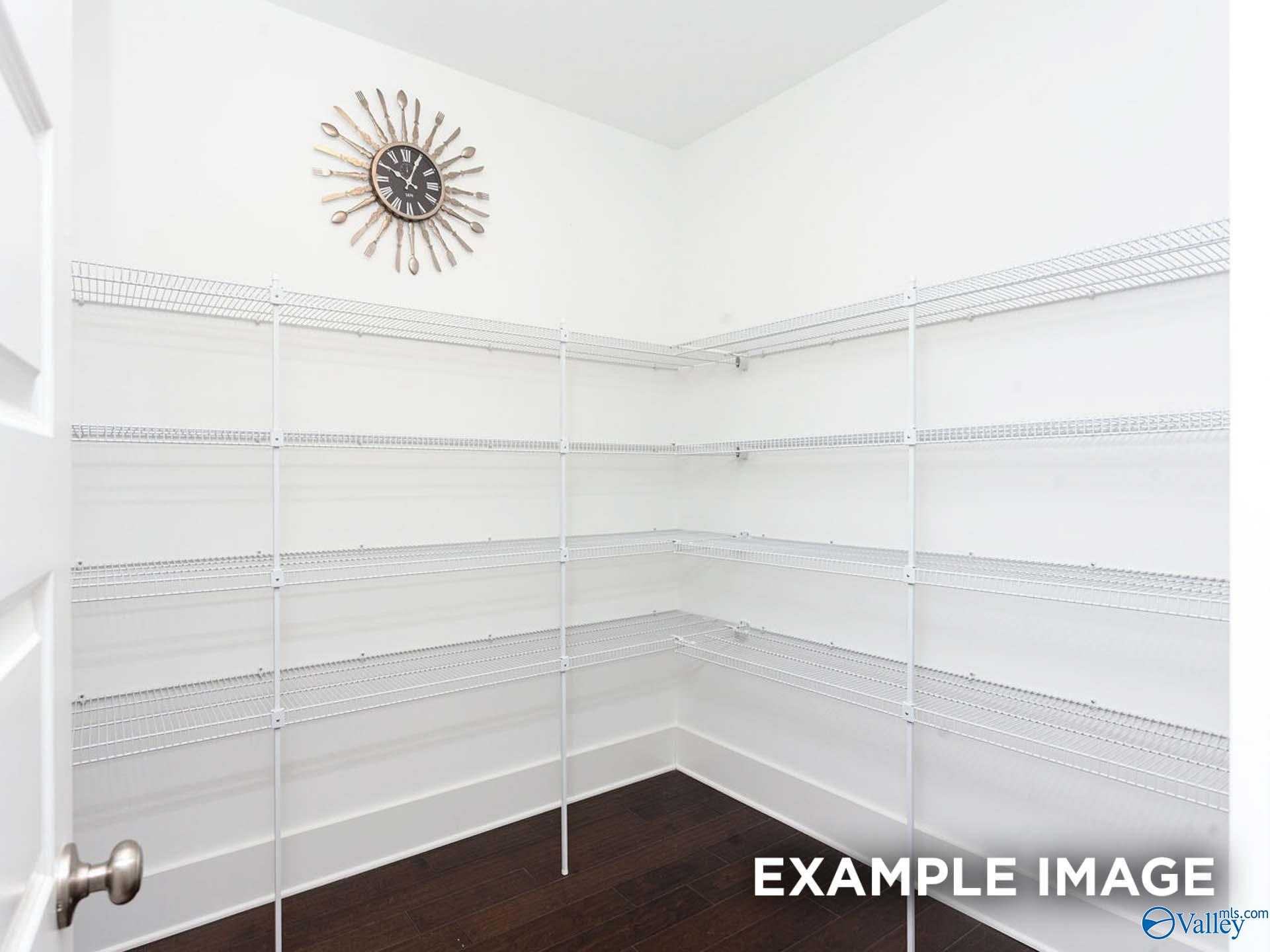 Spacious walk-in closet featuring white wire shelving, hardwood floors, and starburst clock in Davidson Homes The Finleigh, Meridianville, Alabama