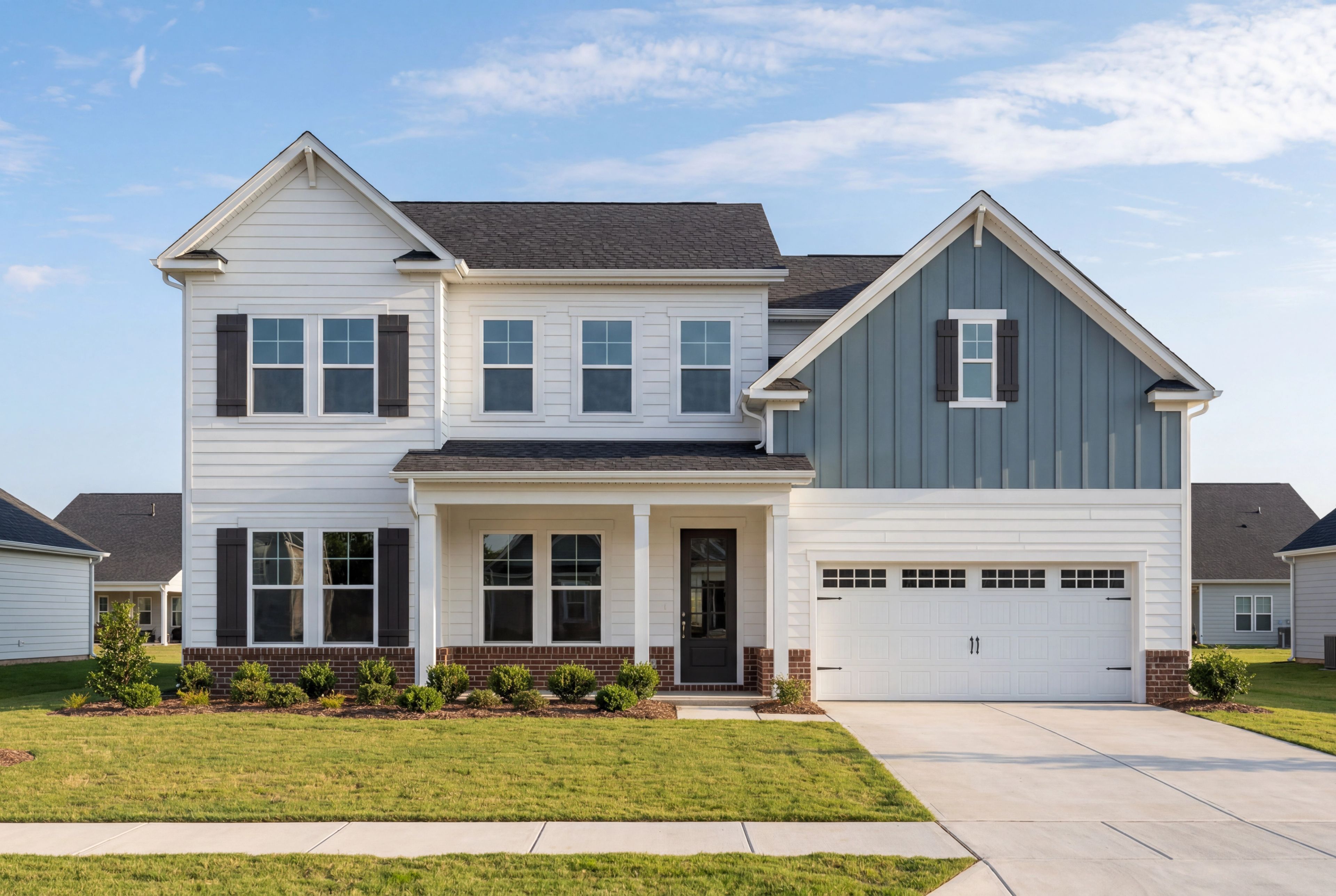 Two-story The Barrington A home elevation with white siding, gray gables, brick accents, covered porch, and two-car garage in Apex NC
