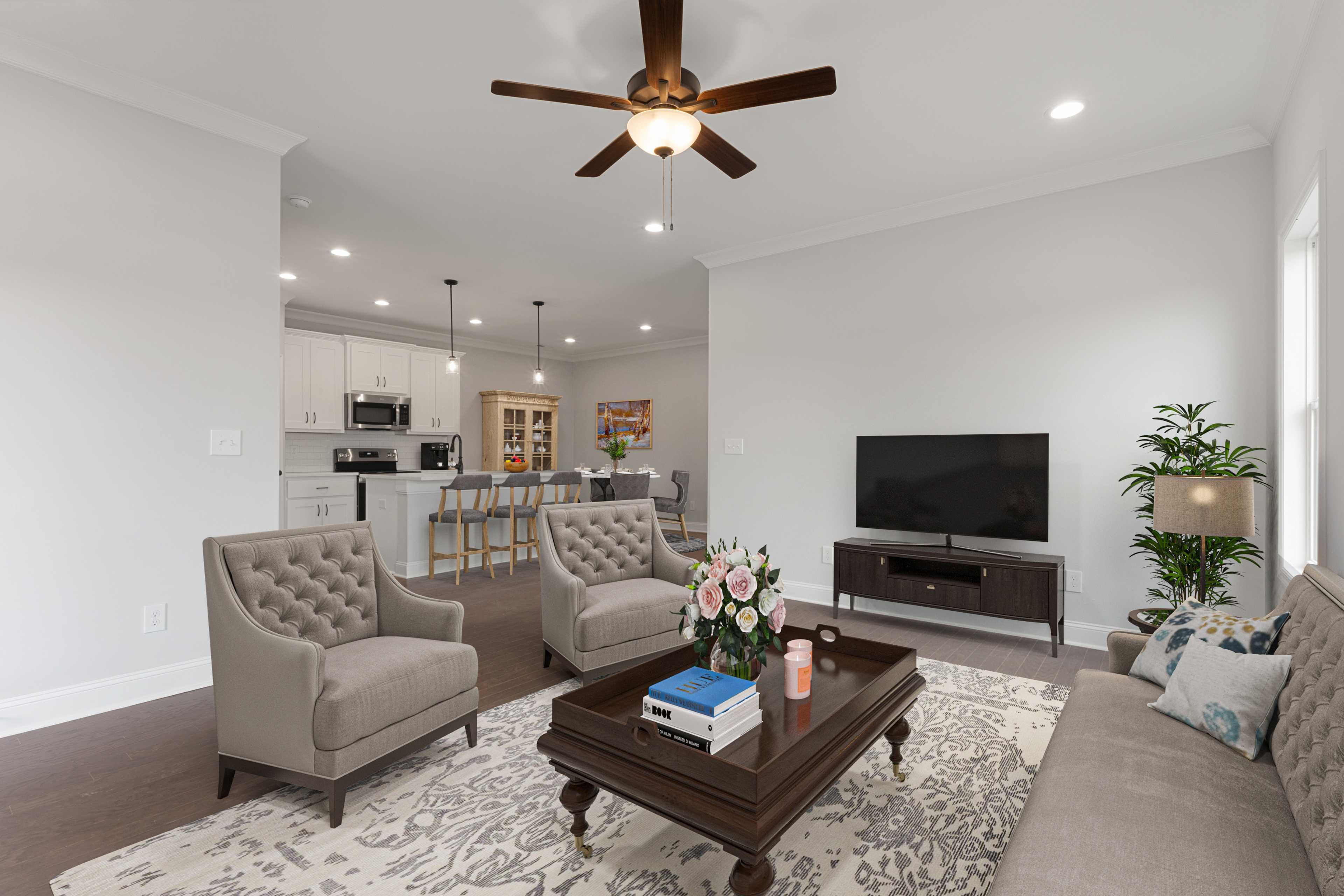 Open-concept living room and kitchen at The Villas at Barnett's Crossing in Madison AL with hardwood floors, ceiling fan, and cozy seating