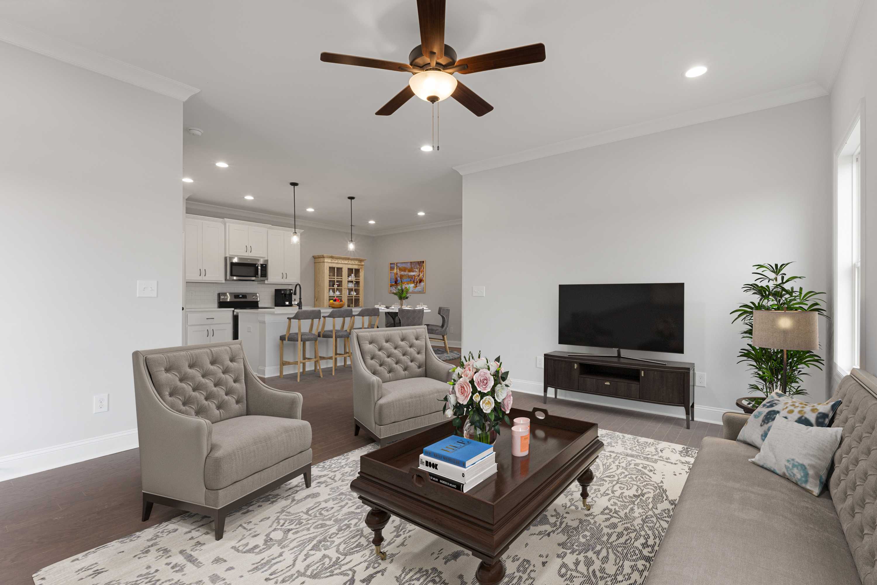 Open-concept living room and kitchen at The Villas at Barnett's Crossing in Madison AL with hardwood floors, ceiling fan, and cozy seating