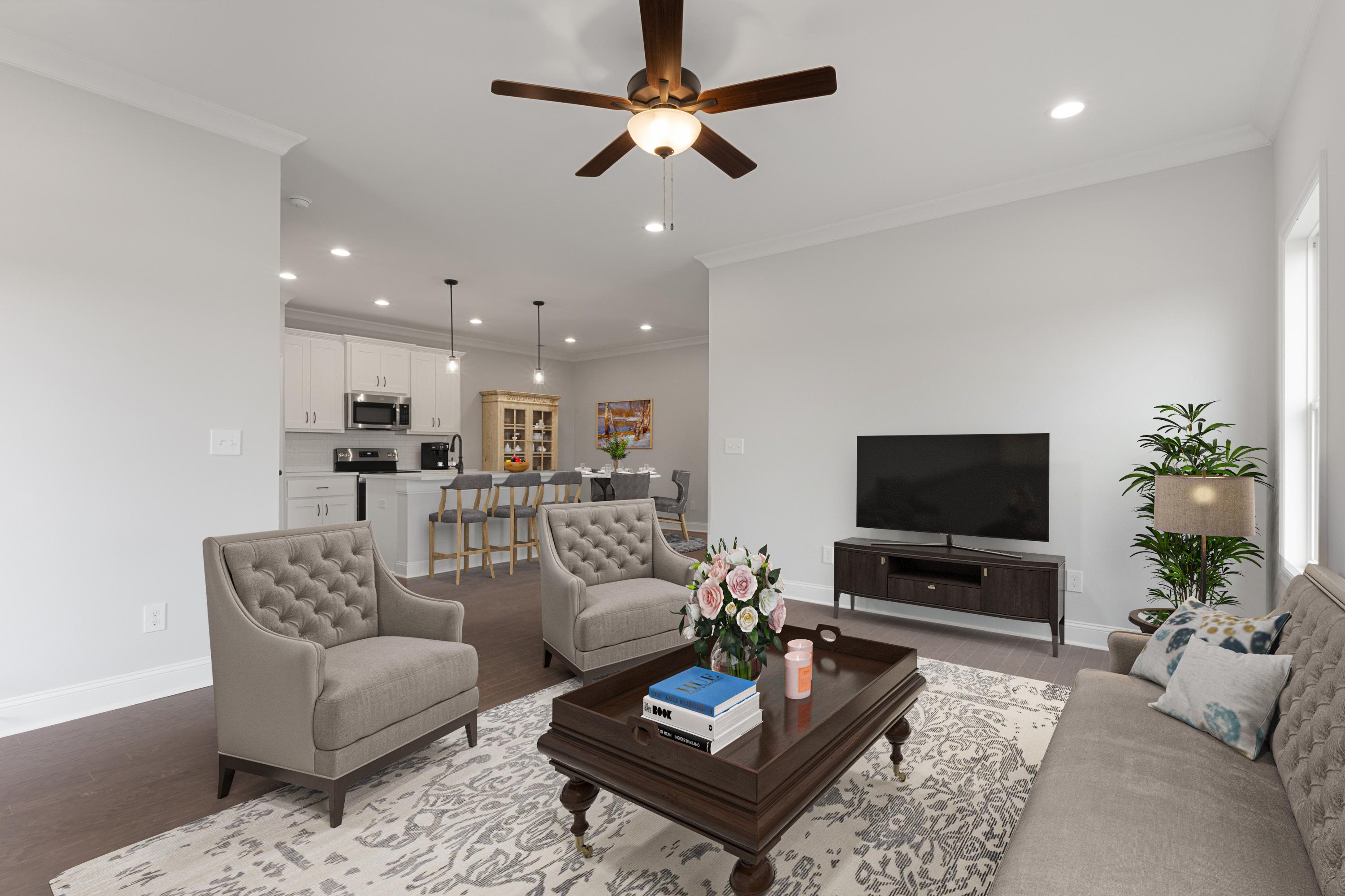 Open-concept living room and kitchen at The Villas at Barnett's Crossing in Madison AL with hardwood floors, ceiling fan, and cozy seating