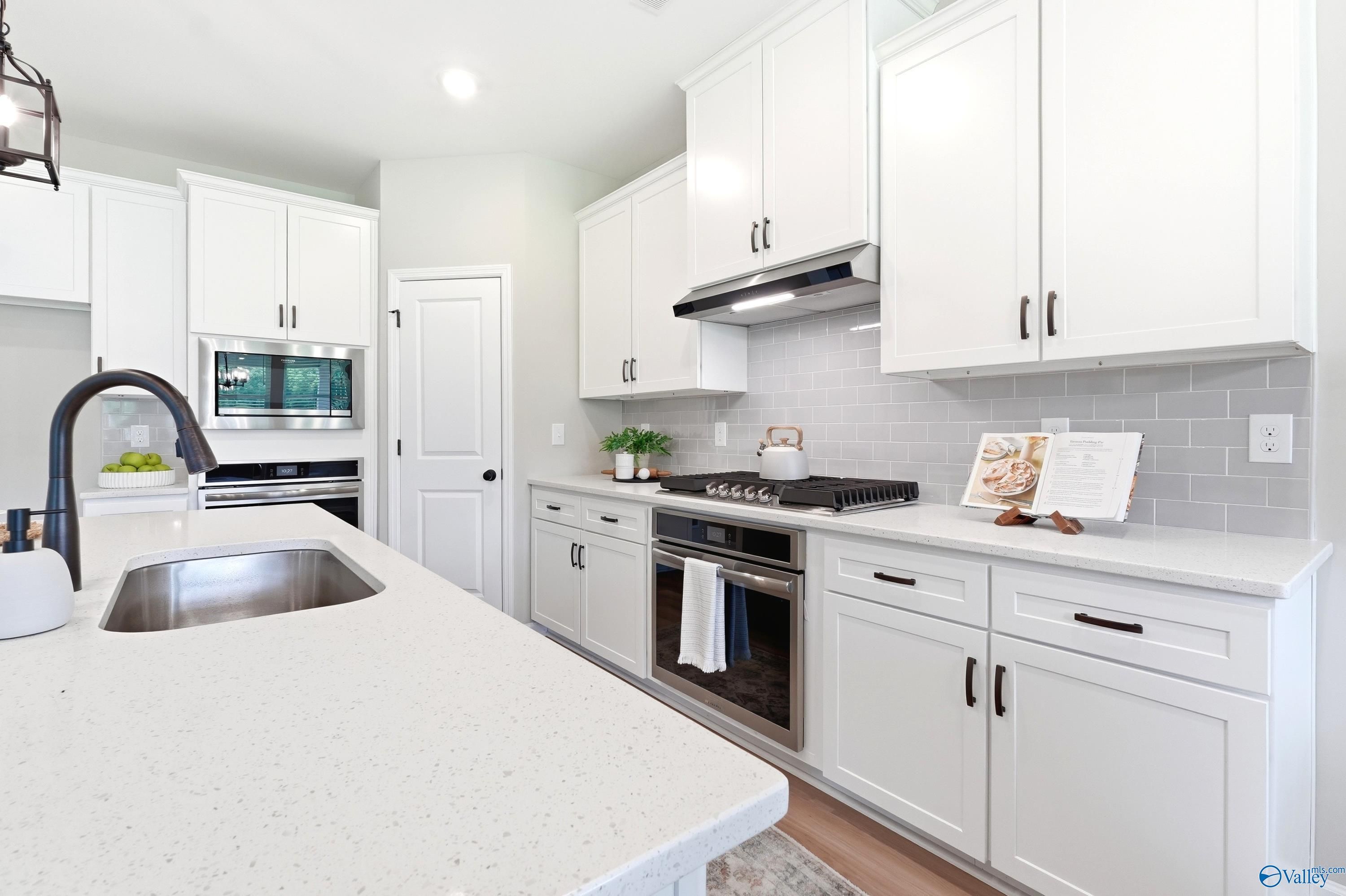 Modern white kitchen with quartz countertops and stainless appliances in The Dorado floor plan, Riverton Preserve, Huntsville.