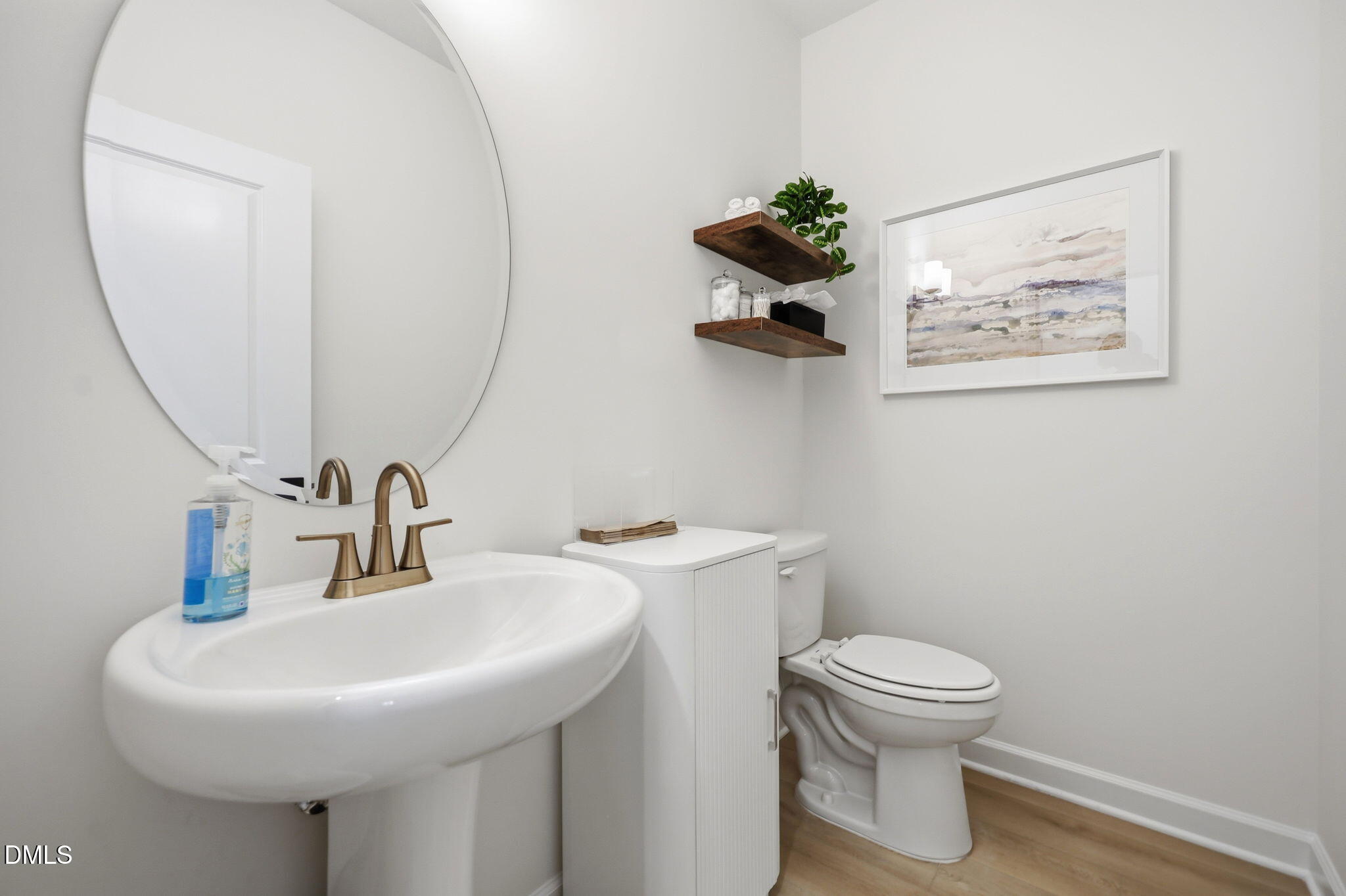Modern half-bathroom with pedestal sink, gold faucet, and circular mirror in The Aspen B floor plan at Wendell Ridge.