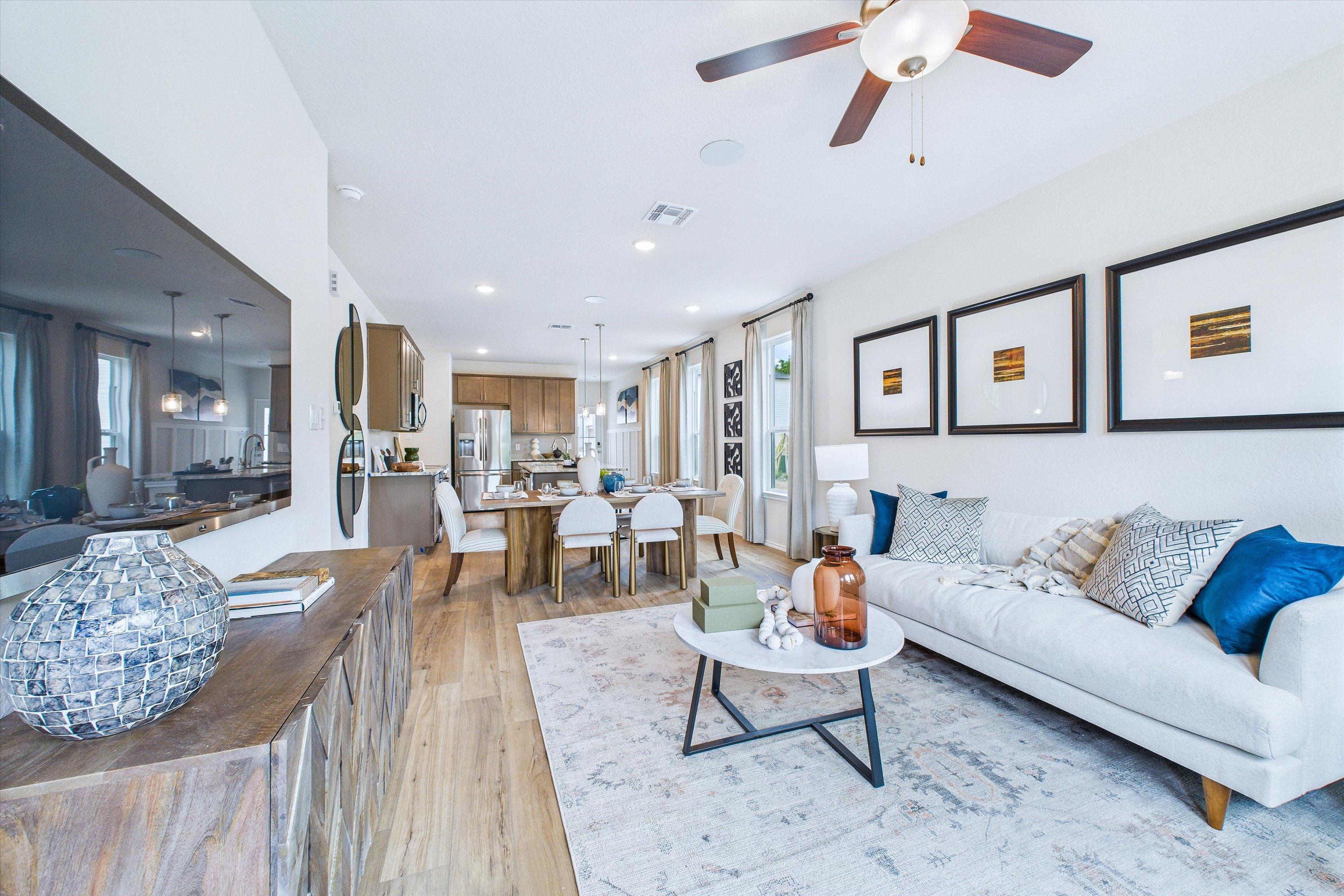 Spacious open-concept living dining kitchen in Cedar Heights San Antonio TX by Davidson Homes with hardwood floors white sofa and ceiling fan
